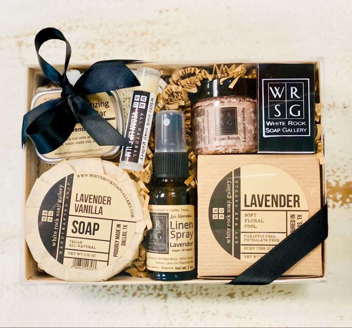 Lavender Love – Self-Care Gift Set - This Lavender gift set makes a perfect gift for anybody and for any occasion. Gift box comes complete with a bow to make gift giving easy.  Gift set contains: Lavender Vanilla Soap, Sisal Soap Pouch, Lavender Soy Wax Candle, Lavender Linen Spray, Lavender Vanilla Sugar Scrub Mini, Lavender Lotion Bar, Lip Balm, and a box of Matches