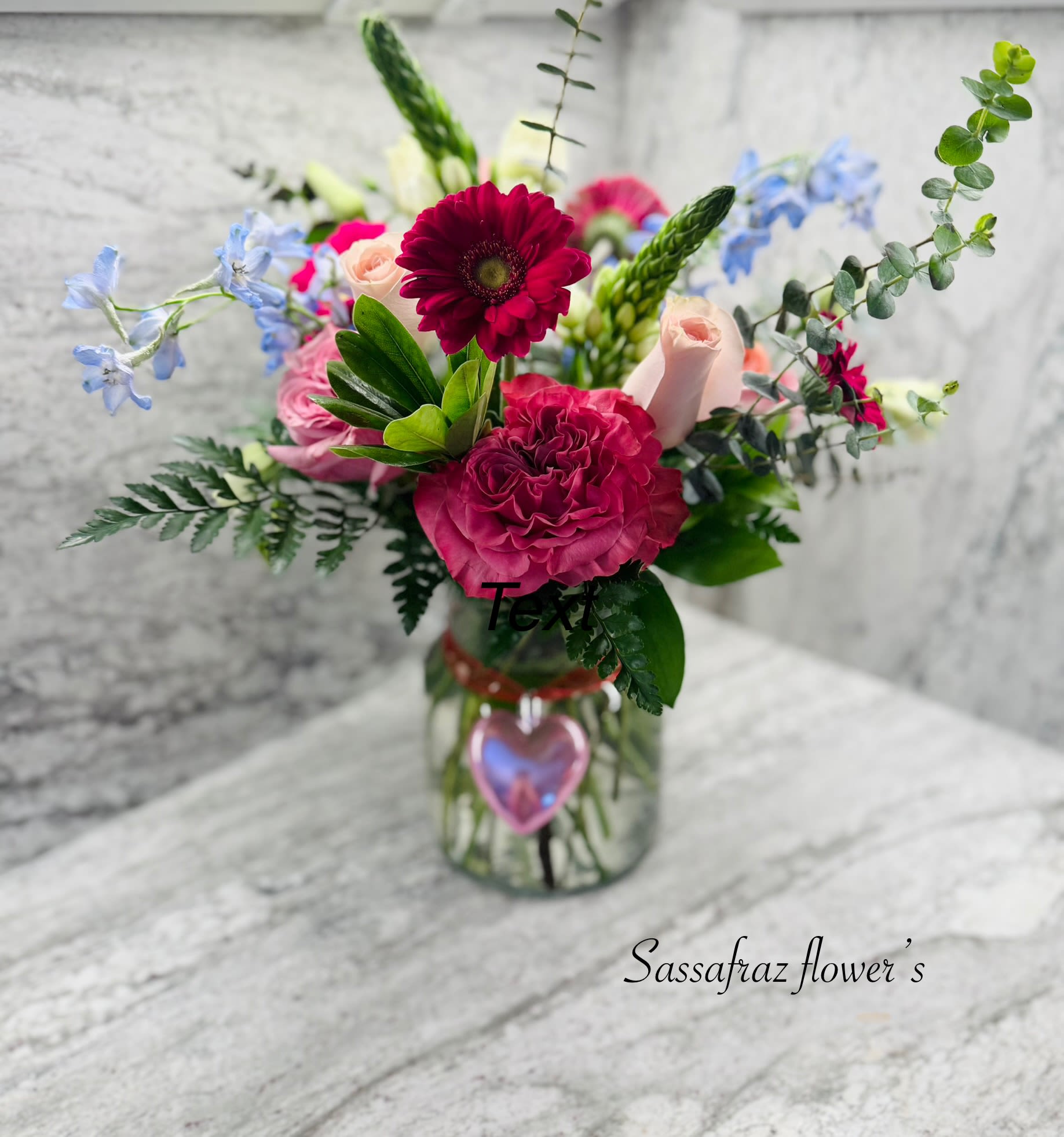 What a Gem - Hot pink jewel tones displayed in a garden style backdrop with day blue delphinium,  night star of bethlehem, eucalyptus, arranged with country blue roses in garden pink and fuchsia gerbera daisies.  
