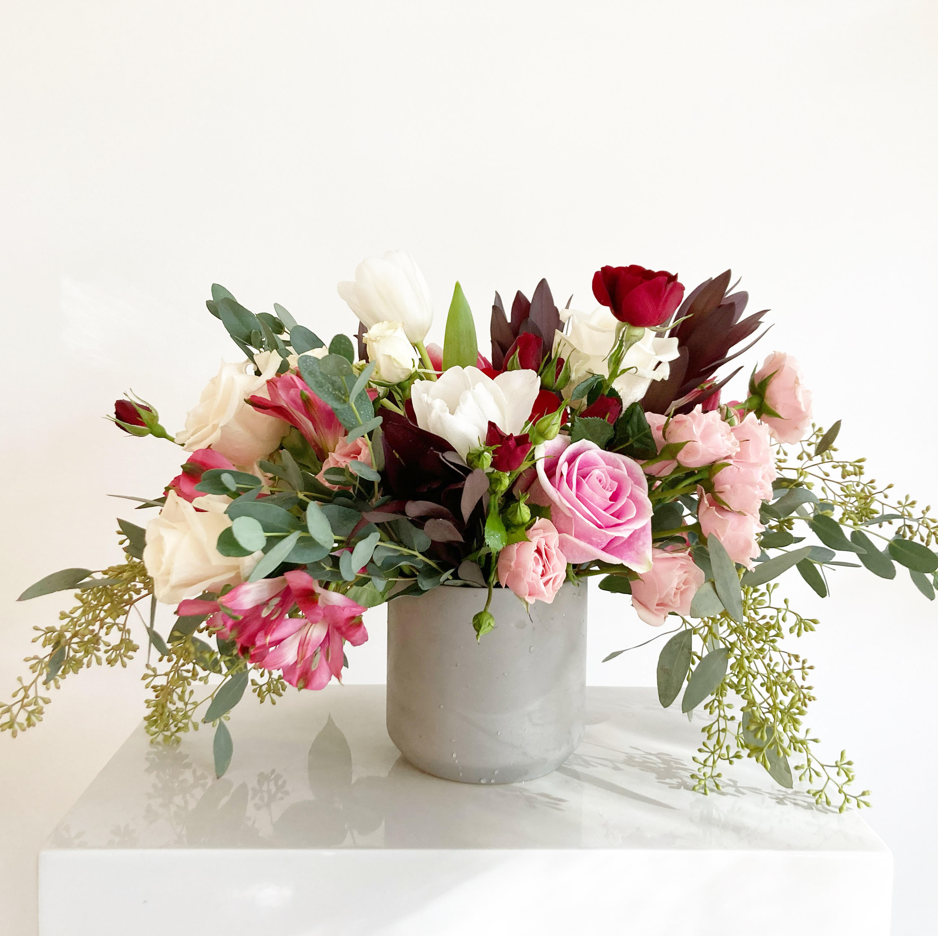 The Gracie - The perfect little vase with white roses and pink, cherry alstroemeria, eucalyptus, Dutch tulips, ruby and pink spray roses and other greenery. Full of fun textures and wonderful for any occasion!