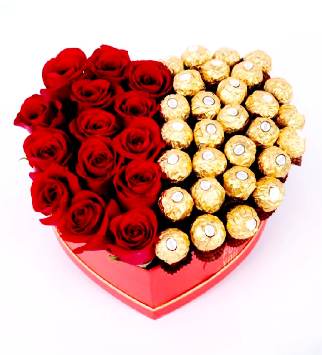 The Great Divide by Pretty in Petals  - This heart-shaped box is divided into two sections: one half features a dense arrangement of red roses, tightly packed for a rich, romantic effect; the other half contains Ferrero Rocher chocolates, each wrapped in gold foil and arranged in a neat grid. The red box with gold trim adds a luxurious and celebratory touch.