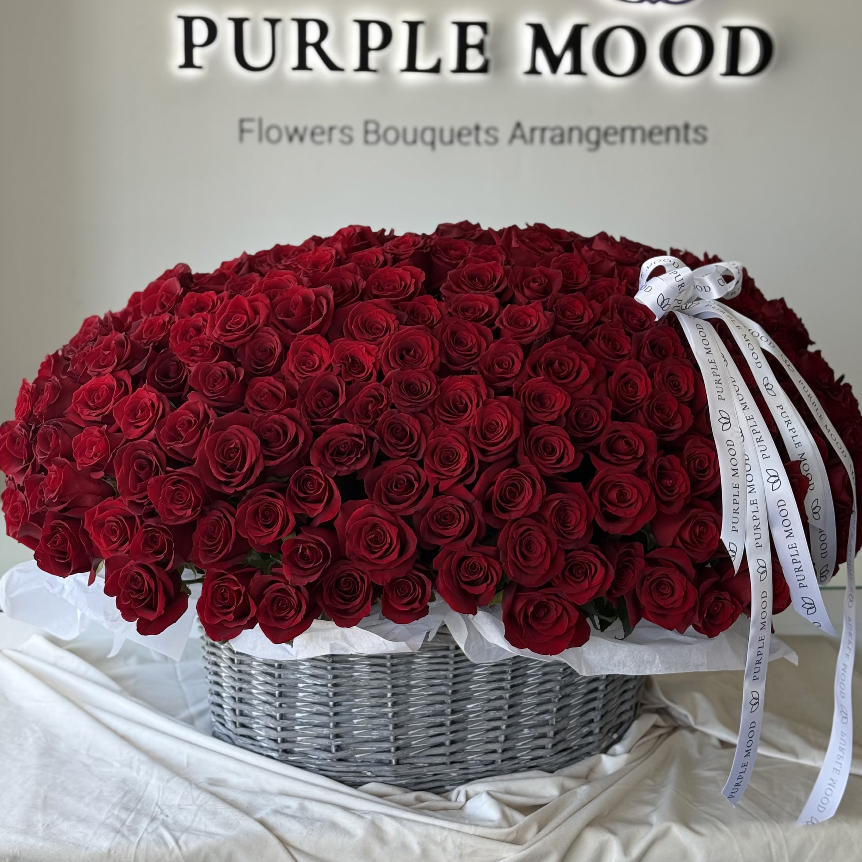 300 Red Roses Basket - A breathtaking grand basket overflowing with 300 premium long-stem red roses, hand-arranged to create an unforgettable sea of love.  Bold. Passionate. Timeless. This masterpiece is designed for those who don’t compromise when it comes to romance. Presented in our signature Purple Mood basket and finished with elegant branded ribbons, this is the ultimate Valentine’s Day statement. 
