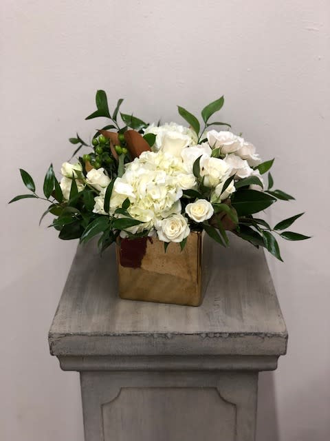 Golden Magnolia - Golden Magnolia Bouquet  Elegant, timeless, and kissed with a hint of holiday shine, the Golden Magnolia Bouquet brings soft beauty and luxe style to any space. A graceful blend of white roses, lisianthus, hydrangeas, spray roses, and hypericum berries is accented with seeded eucalyptus and glossy magnolia leaves, creating a stunning arrangement full of texture and sophistication.  Presented in a chic keepsake gold cube—perfect for repurposing with a votive for a warm, glowy touch. Prefer silver? We’re happy to swap the container to a gold OR silver cube upon request—just let us know in the Special Instructions at checkout.  Flowers and container may vary based on availability, ensuring each bouquet remains fresh and unique.