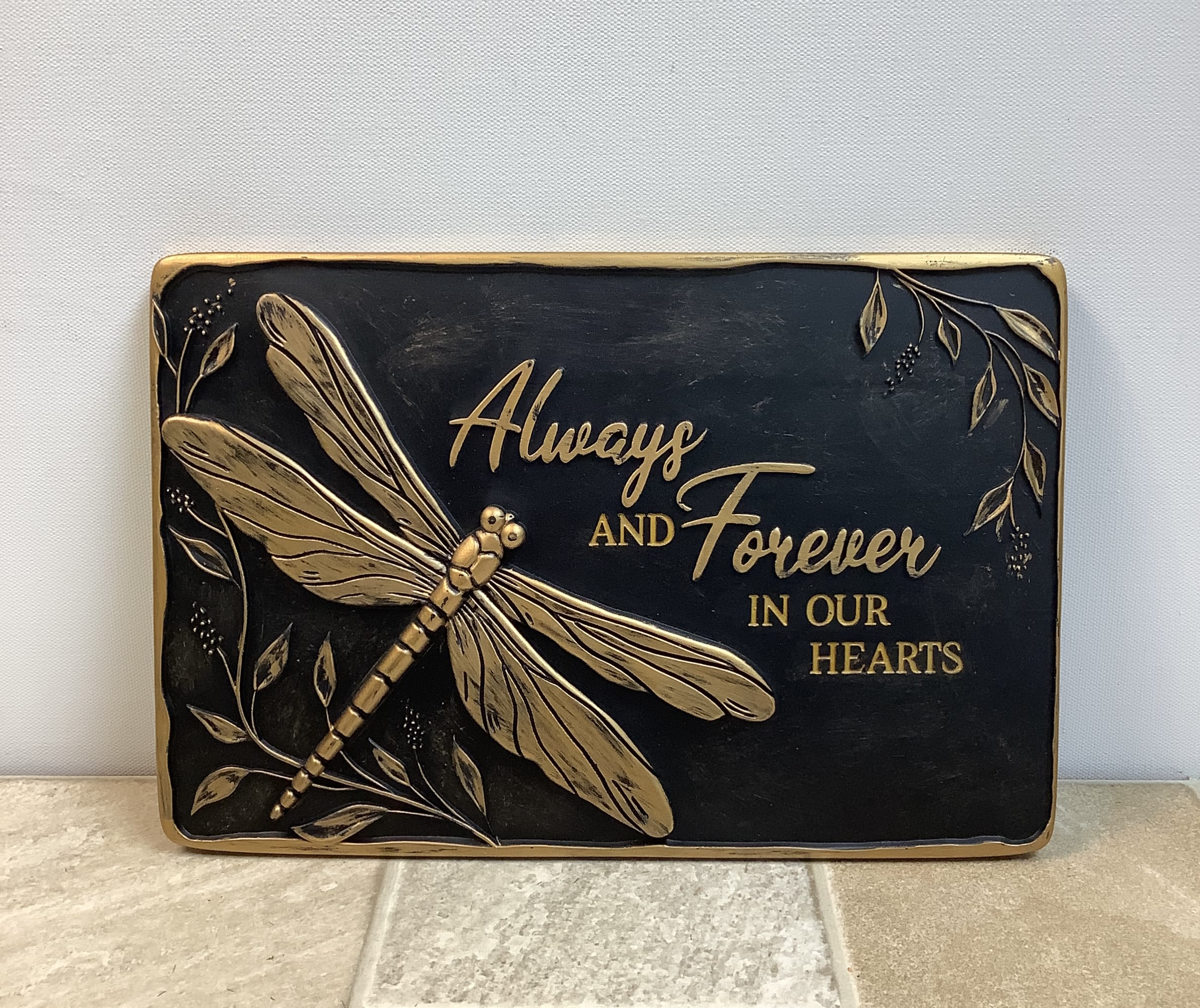 Plaque - dragonfly - This keepsake rectangular decorative plaque is perfect as a memorial or garden stepping stone. It has a black background with gold-colored accents and a large, dragonfly with the saying "Always and Forever in Our Hearts". 12" wide x 8" high.