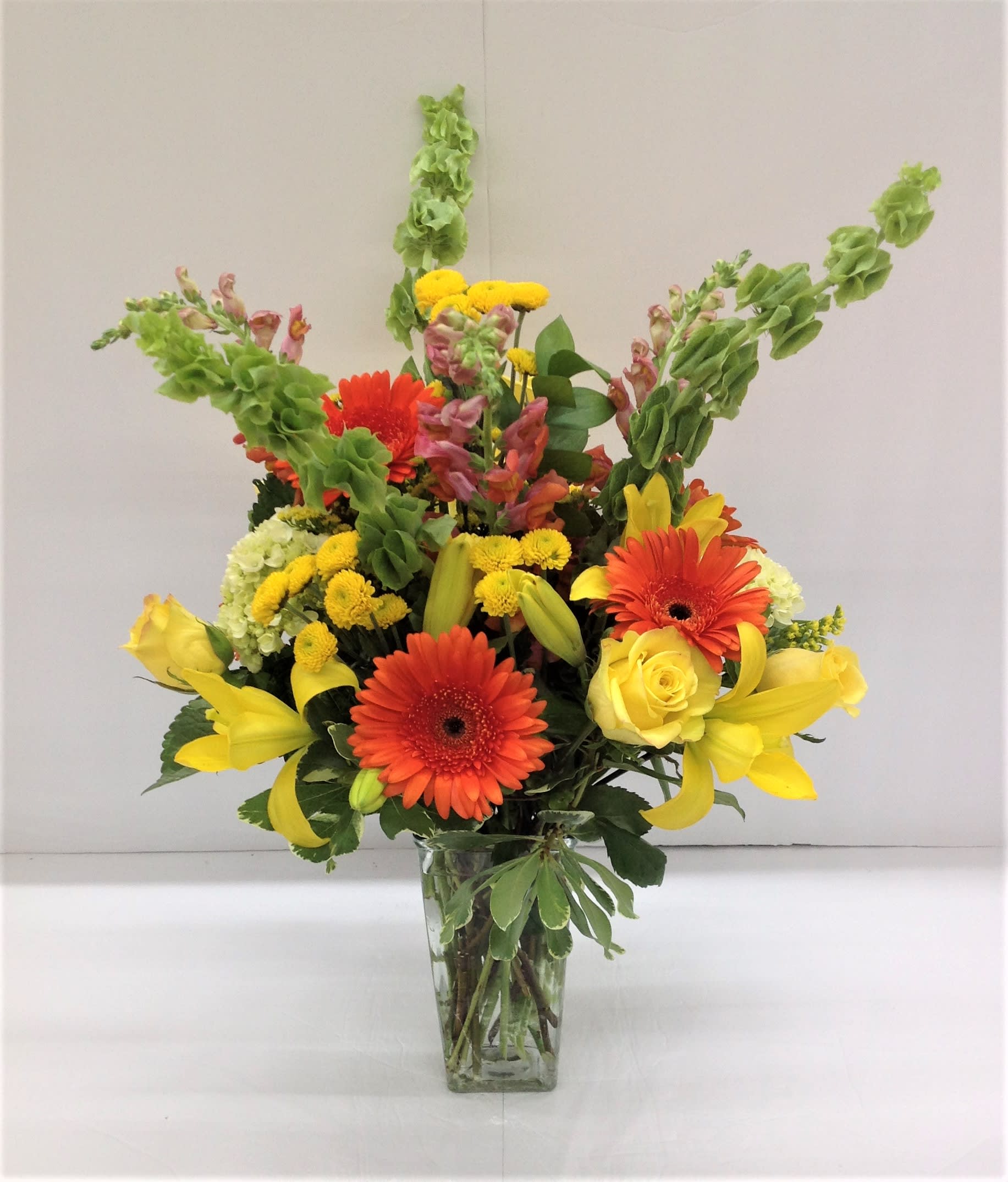 All the Sun-Rage - Orange, green, yellow and a touch of pink... gerbers, lilies, roses, bells of Ireland, buttons, snapdragons, mini hydrangea, solidago and more...  Flowers may vary depending on availability.  FCF-223 