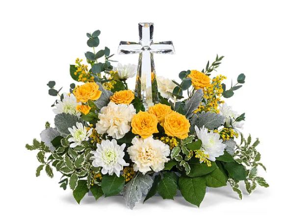 Graceful Sunset Cross Bouquet - A crystal cross centerpiece is surrounded by the soft glow of yellow roses, yellow and white carnations, white daisey poms, white larkspur, and yellow snapdragons on a bed of greens.