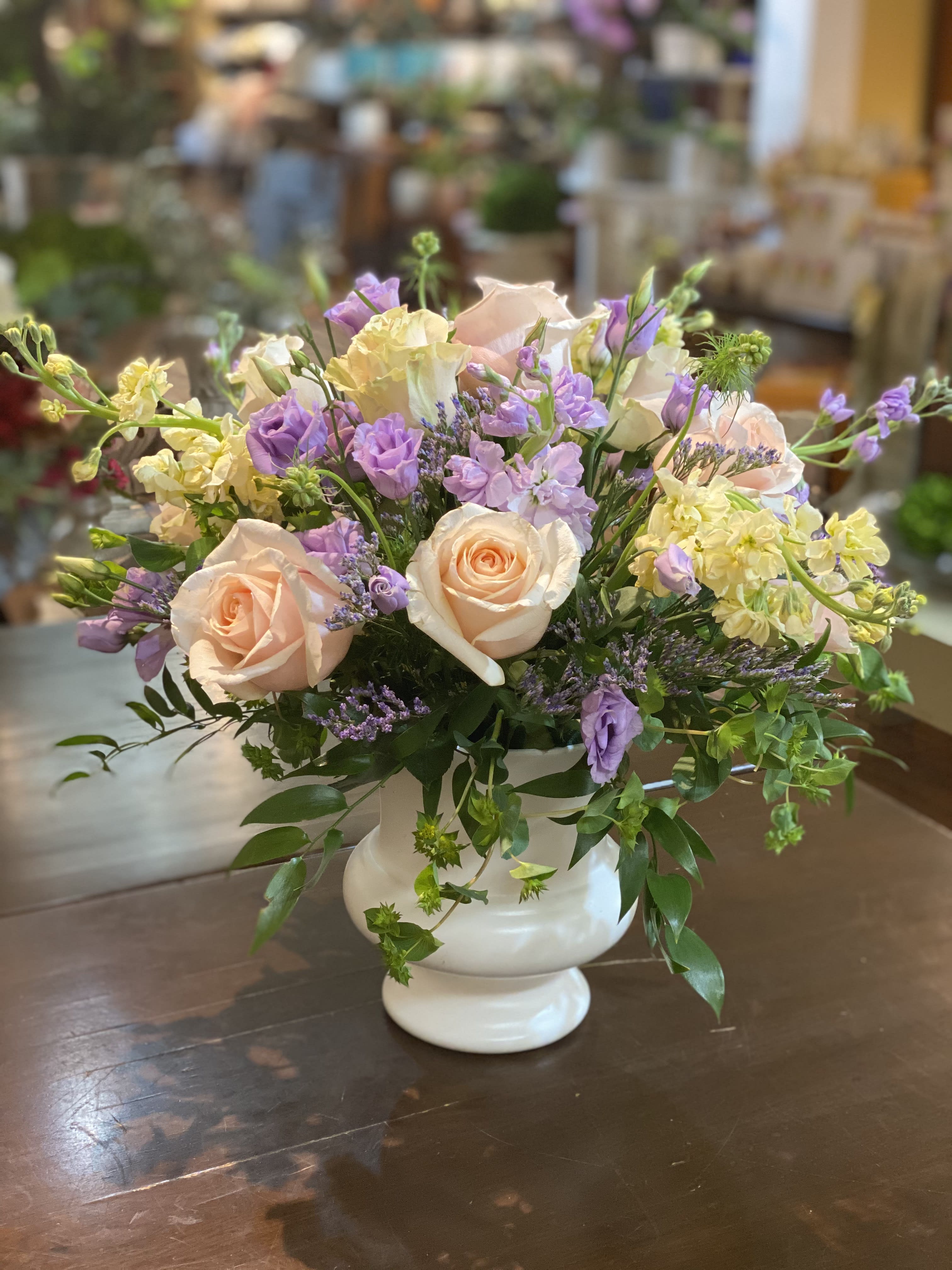 Pastel Garden - This charming garden-style arrangement of soft pastel colors adds a classic touch suitable for any setting. Includes rose, stock and lisianthus lusciously displayed in a white plastic urn.  