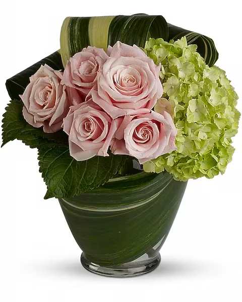 Cosmopolitan Pink - Happy anniversary or any happy occasion, this delightful bouquet of pink roses and green hydrangea is a lovely choice. Simple yet sophisticated, it is guaranteed to elicit lots of oohs and aahs.  The stylish bouquet includes green hydrangea and pink roses accented with aspidistra leaves. Delivered in a glass serenity vase lined with variegated aspidistra leaves.  Orientation : One-Sided All prices in USD ($) Due to an increase in the cost of roses, some product prices may be impacted during the Valentine’s delivery period.
