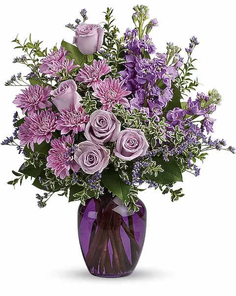 Together At Twilight Bouquet - Capture the magic of togetherness with this bountiful bouquet of enchanting lavender roses. Artfully arranged in a glass vase, its twilight hues are sure to brighten anyone's day!  This dramatic arrangement includes lavender roses, lavender stock, lavender cushion spray chrysanthemums, lavender limonium, oregonia and lemon leaf. Delivered in a purple glass vase.  Orientation : One-Sided All prices in USD ($) Due to an increase in the cost of roses, some product prices may be impacted during the Valentine’s delivery period.