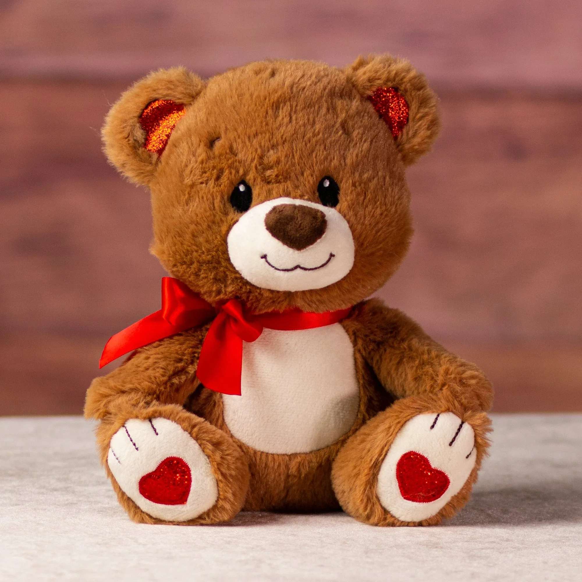 Glittery Valentine Bear 9" - Glitzy and nice, this brown bear sports a pleasant smile and sparkly hearts on its feet with matching colors in its ears. Great for Valentine's Day. Soft and cuddly, stuffed with hypoallergenic fiber fill.