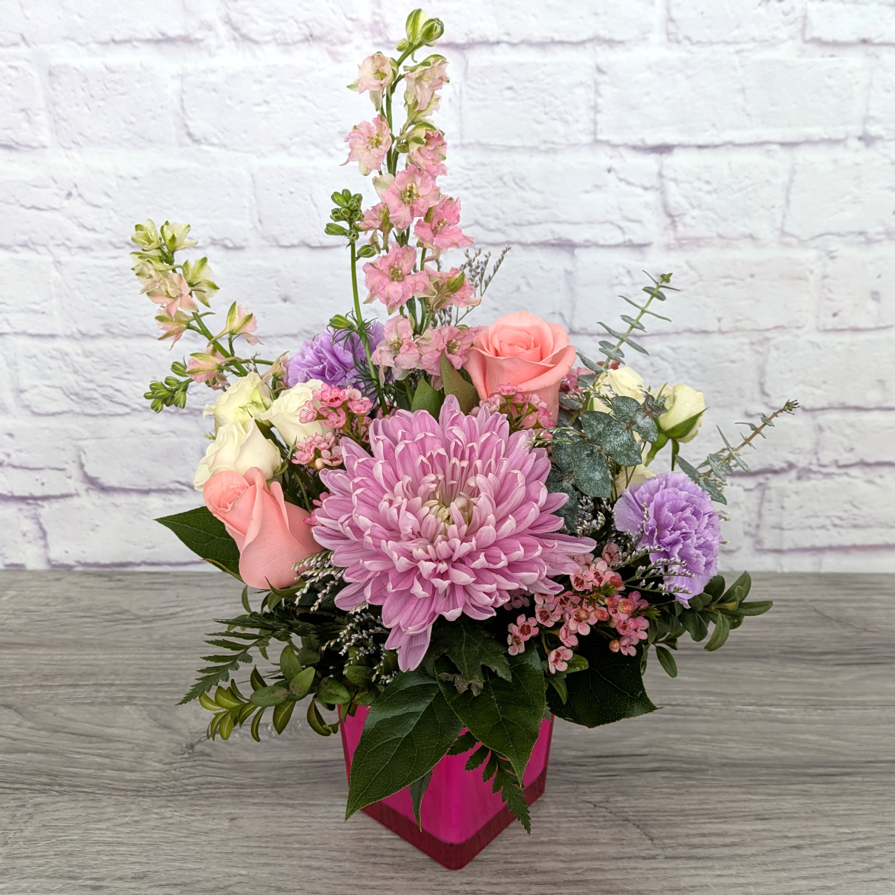Hi Barbie! - Hi Barbie! is A Ladybug Floral Exclusive bouquet.  This bouquet features larkspur, roses, spray roses, football mums, carnations, wax flower, limonium and spiral eucalyptus, all within a hot pink 4.5” cube.  Orientation: All Around 16” Tall 12” Wide  