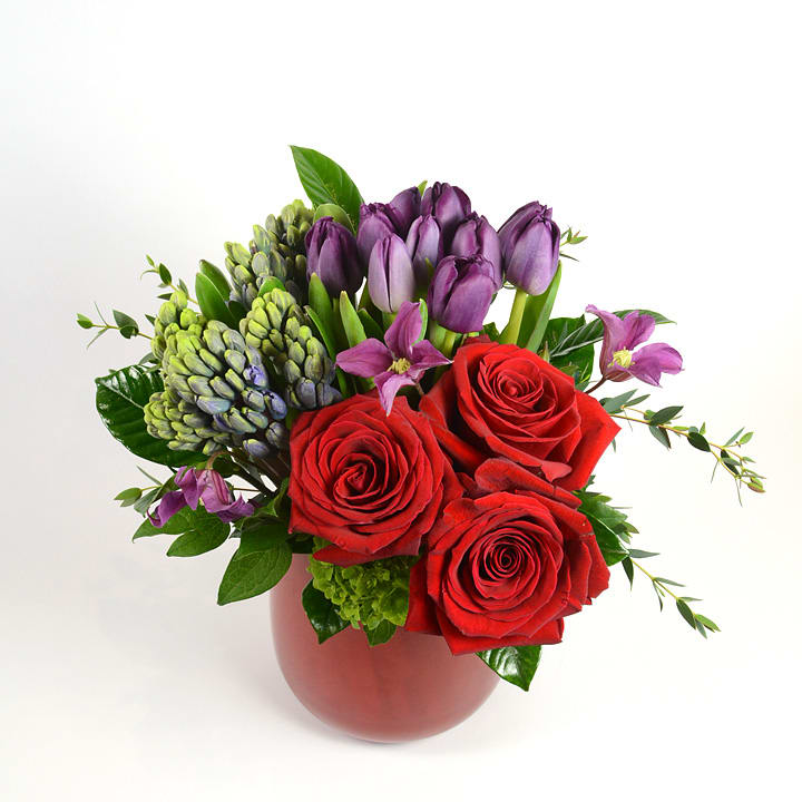 PS I Love You - Fragrant Dutch hyacinth, purple tulips and red roses accented with clematis in our red glass vase. A combination built for love. 