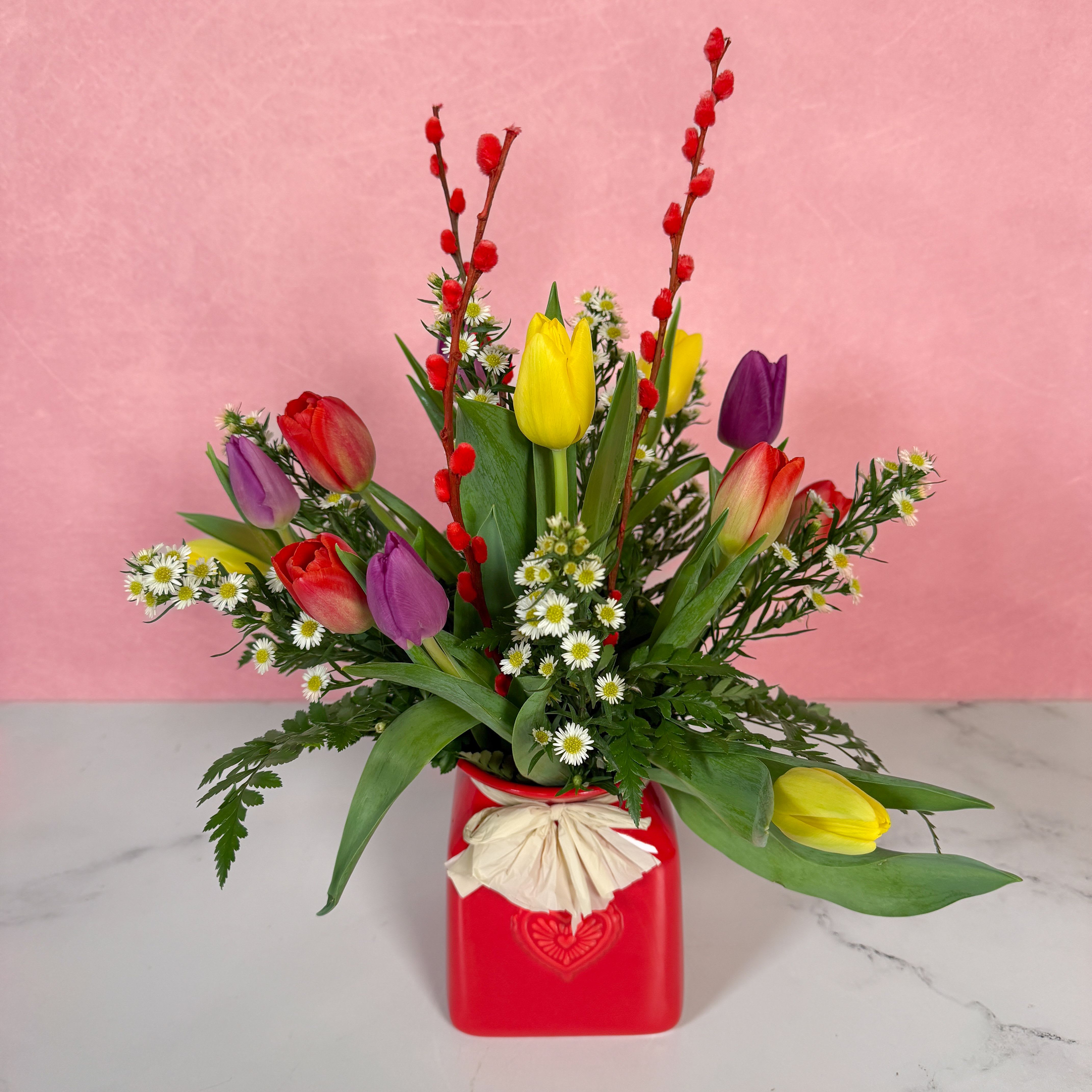 Treasured Tulips - Give your valentine a burst of spring with our Treasured Tulips! Assorted, colorful tulips are artfully arranged in a red ceramic vase embellished with a heart on it to emphasize your love. These blooms are the perfect blend of Valentine's Day and spring, sure to brighten the day of anyone who receives our lovely Treasured Tulips.