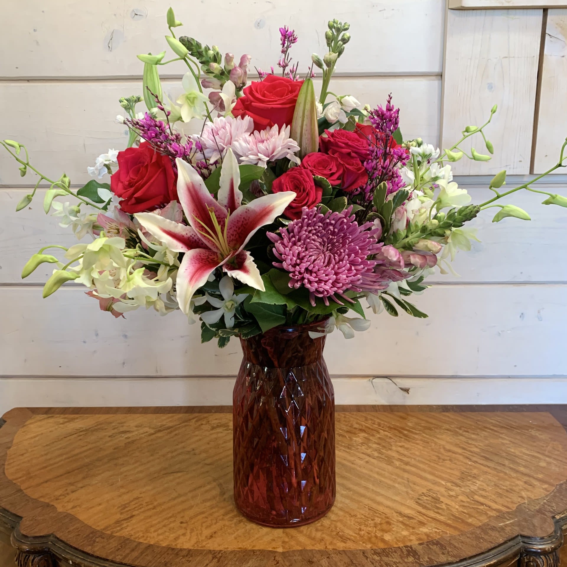 Enchanted Love Bouquet - Stargazer lilies, white orchids and hot pink roses with hot pink spray roses, lavender snapdragons, fragrant white stock, and lavender chrysanthemums arranged in a tall pink cut glass posie vase with pink alstroemeria and pink ginestra. Approximately 13" wide and 20" tall.