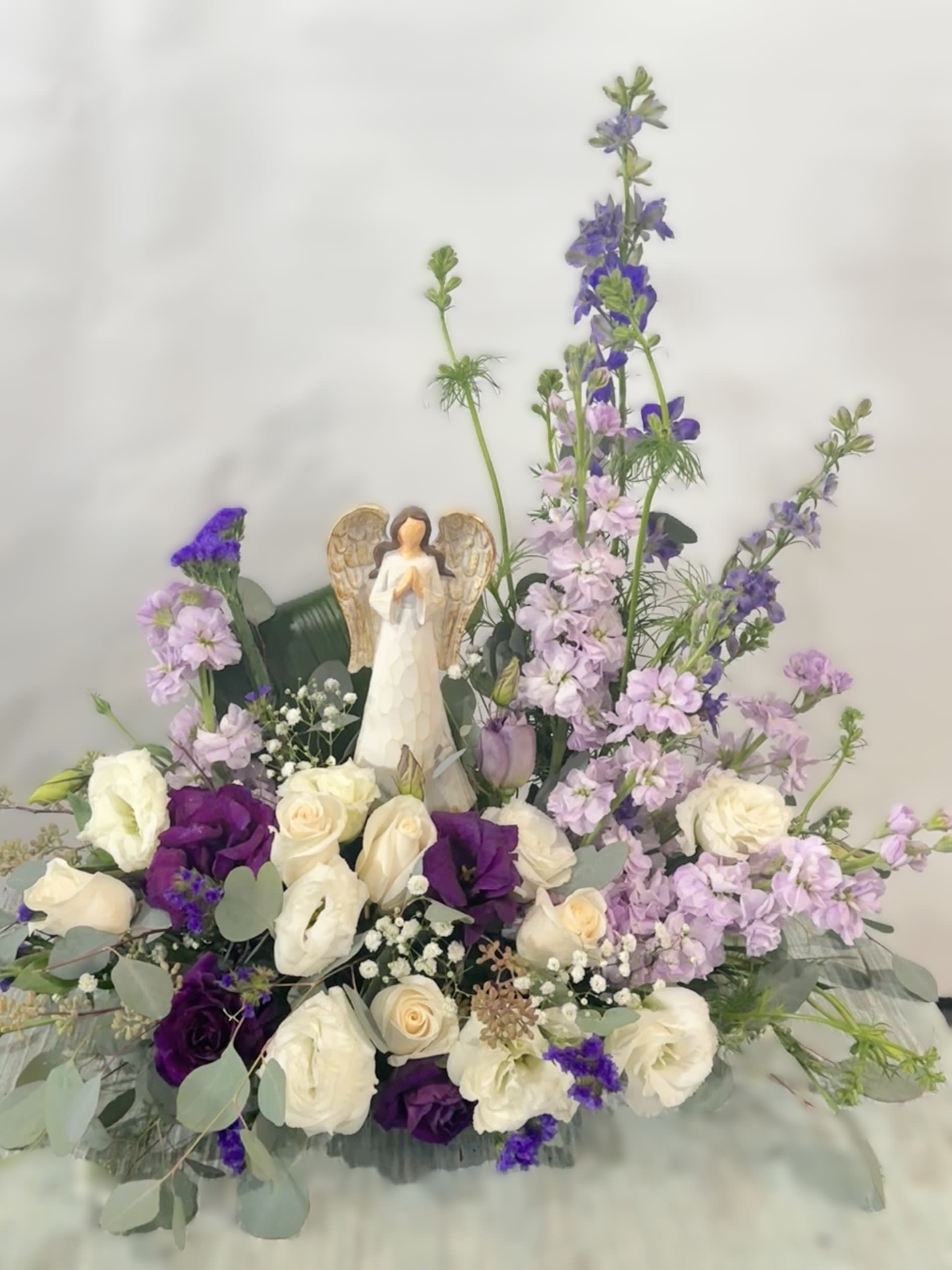 Sympathy Statue Arrangement #10 - White and purple arrangement which includes an angel statue. If statue is out of stock it will be substituted with a similar statue. Color can be modified depending on availability.