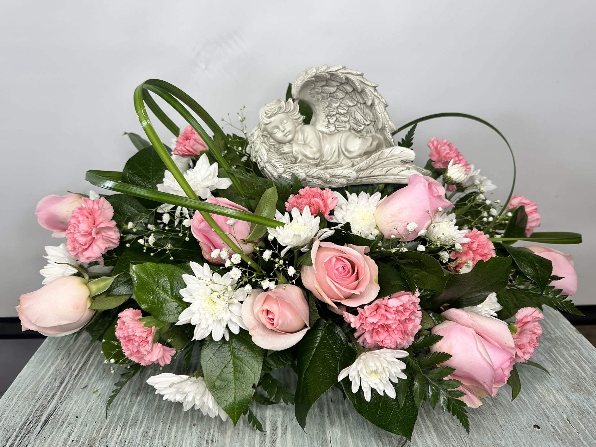 Sympathy Statue Arrangement #18 - Pink and white arrangement which includes a laying angel statue (statue dimensions 5" H x 8.5" L x 4.25" W). If statue is out of stock it will be substituted with a similar statue. Color can be modified depending on availability.