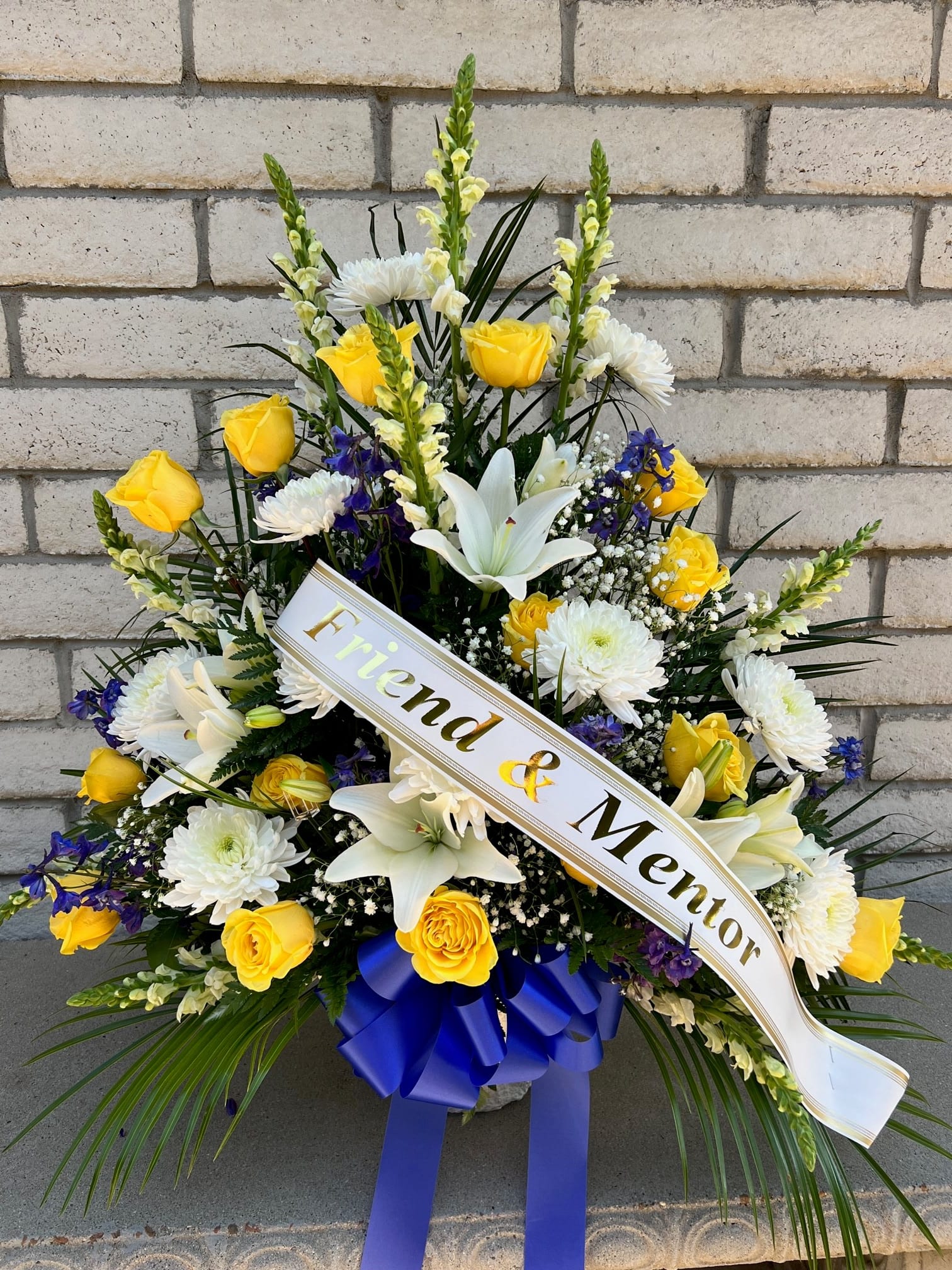 Sympathy #25 - Sympathy arrangement of fresh cut flowers designed in a paper mache container. Embellished with a Bow. Colors can be modified depending on availability. Banner is included with arrangement. Please specify what is to be printed on banner upon check out under "FLORIST INSTRUCTIONS". LIMITED TO 5 WORDS ON BANNER.