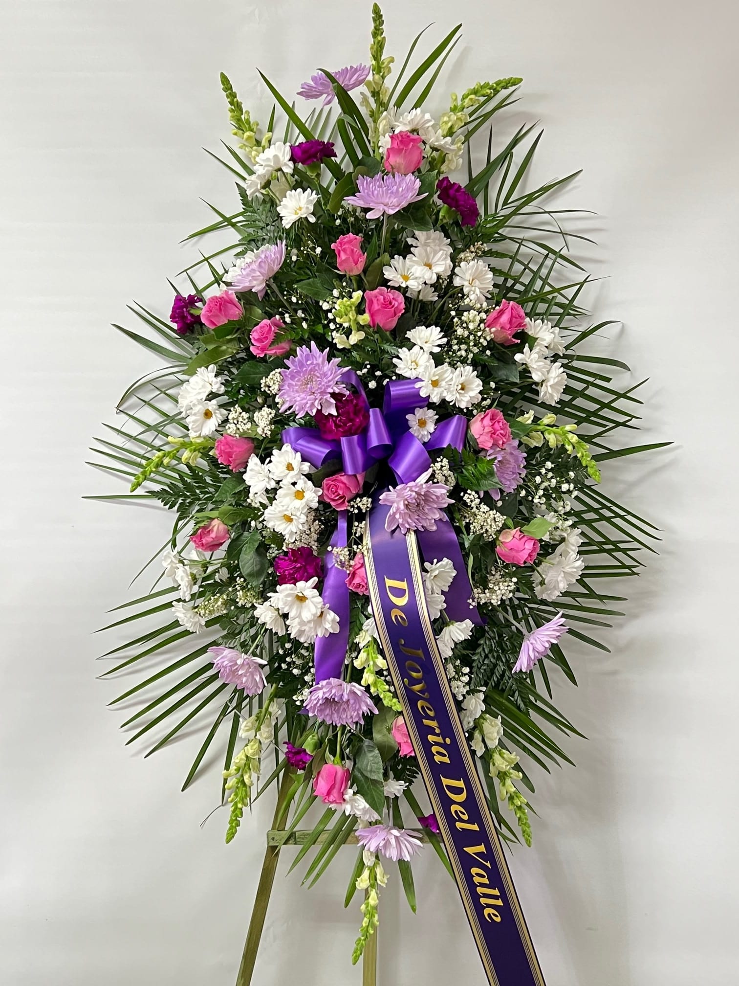 Sympathy Standing Spray #37 - Standing spray of white, lavender and purple fresh cut flowers. Embellished with a purple bow. Colors can be modified depending on availability. Designed on an easel which is included with arrangement and does NOT need to be returned. Banner is included with arrangement. Please specify what is to be printed on banner upon check out under "FLORIST INSTRUCTIONS". LIMITED TO 5 WORDS ON BANNER.