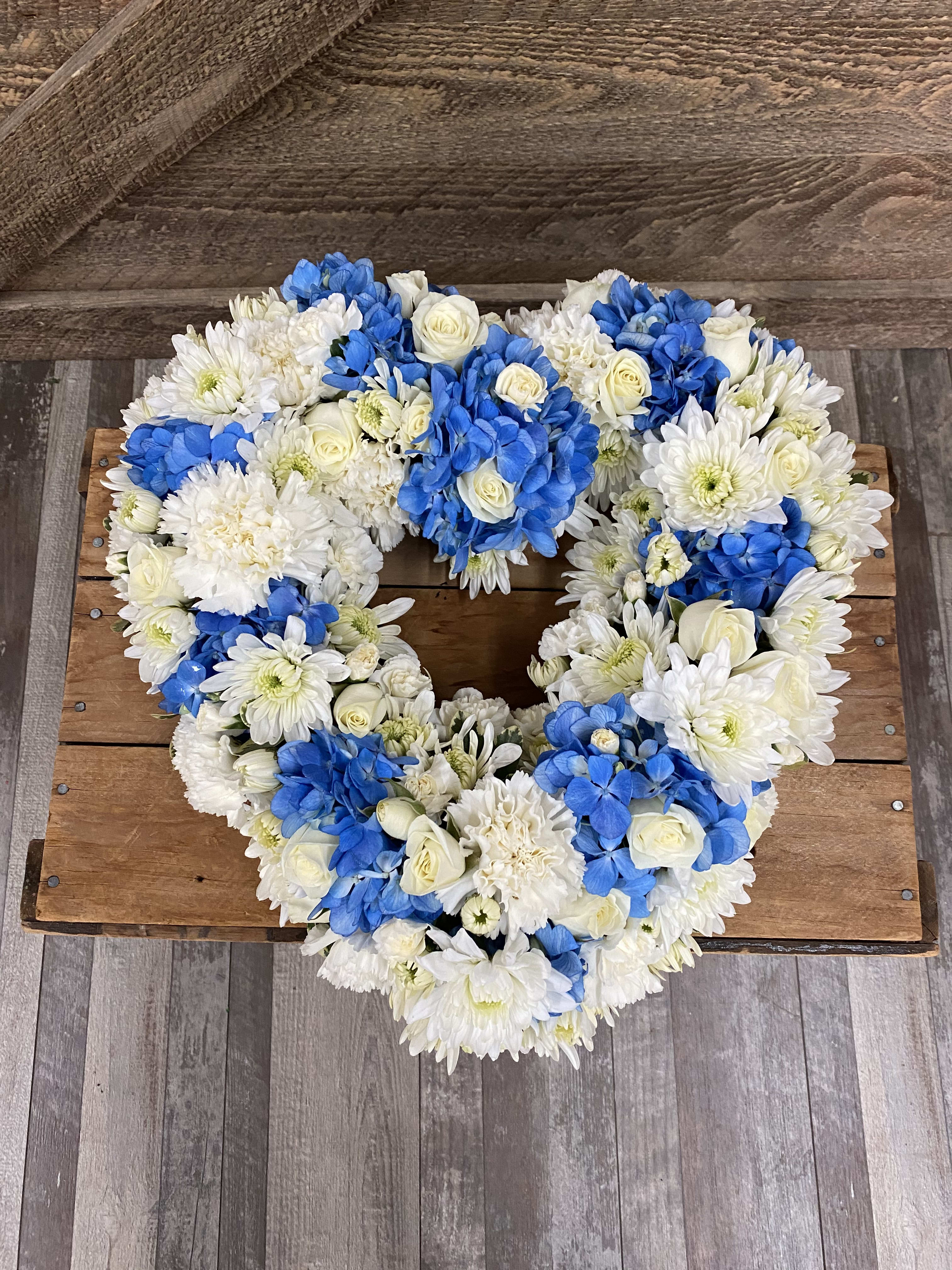 Small Blue And White Heart Wreath - This blue and white small open heart wreath includes hydrangea, mini roses, mums and fillers. Please let us know if you would like to change the colors. We'd be happy to fulfill any special requests. 