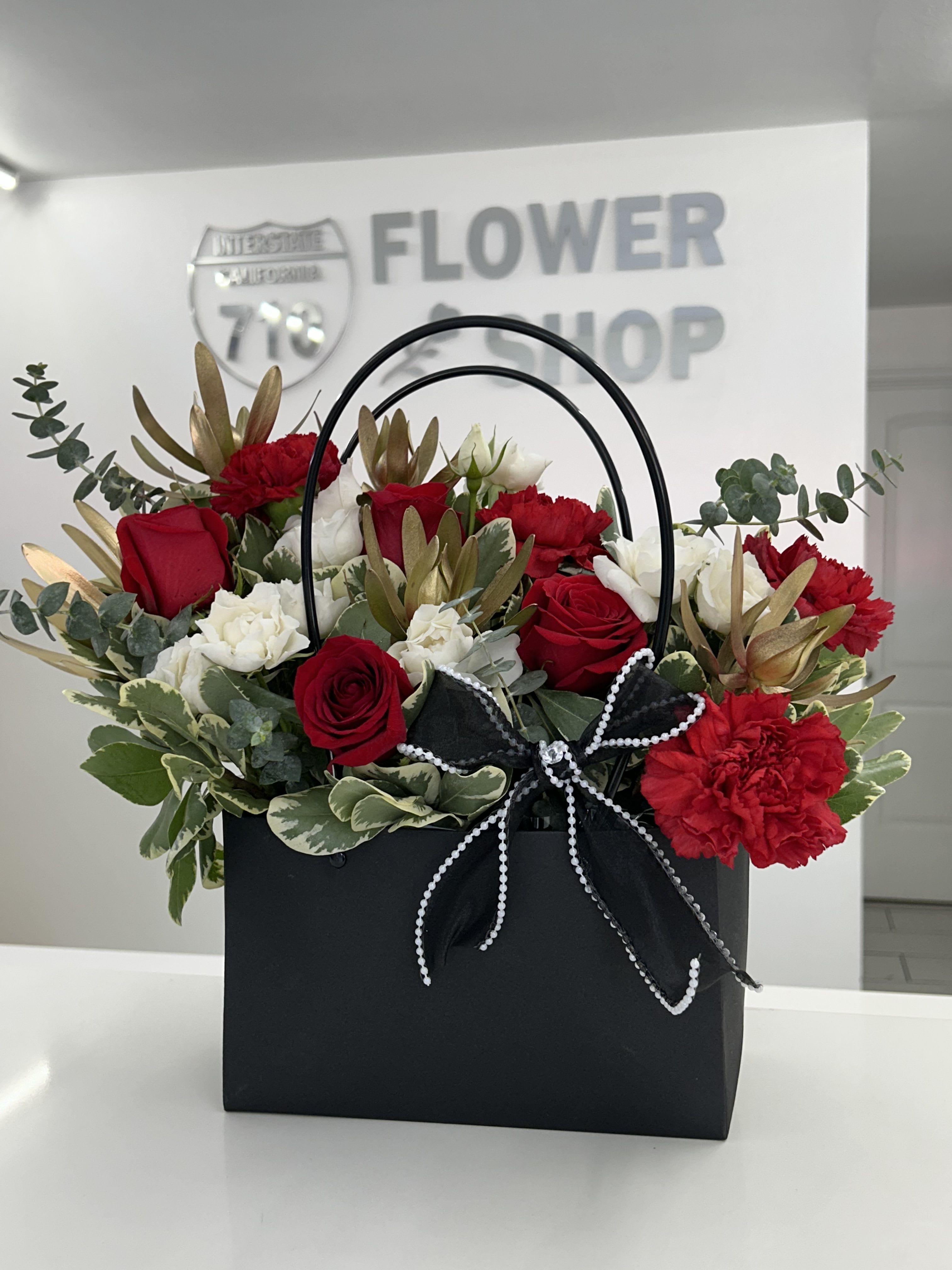 Midnight Romance - A bold and luxurious arrangement designed to impress. Midnight Romance is styled in a chic black handbag box and finished with a pearl-trimmed black bow, this arrangement is perfect for romantic gestures, anniversaries, Valentine’s Day, or when you want to make a dramatic statement of love and sophistication. (If some flowers and/or the vase are not available there will be minor substitutions.)