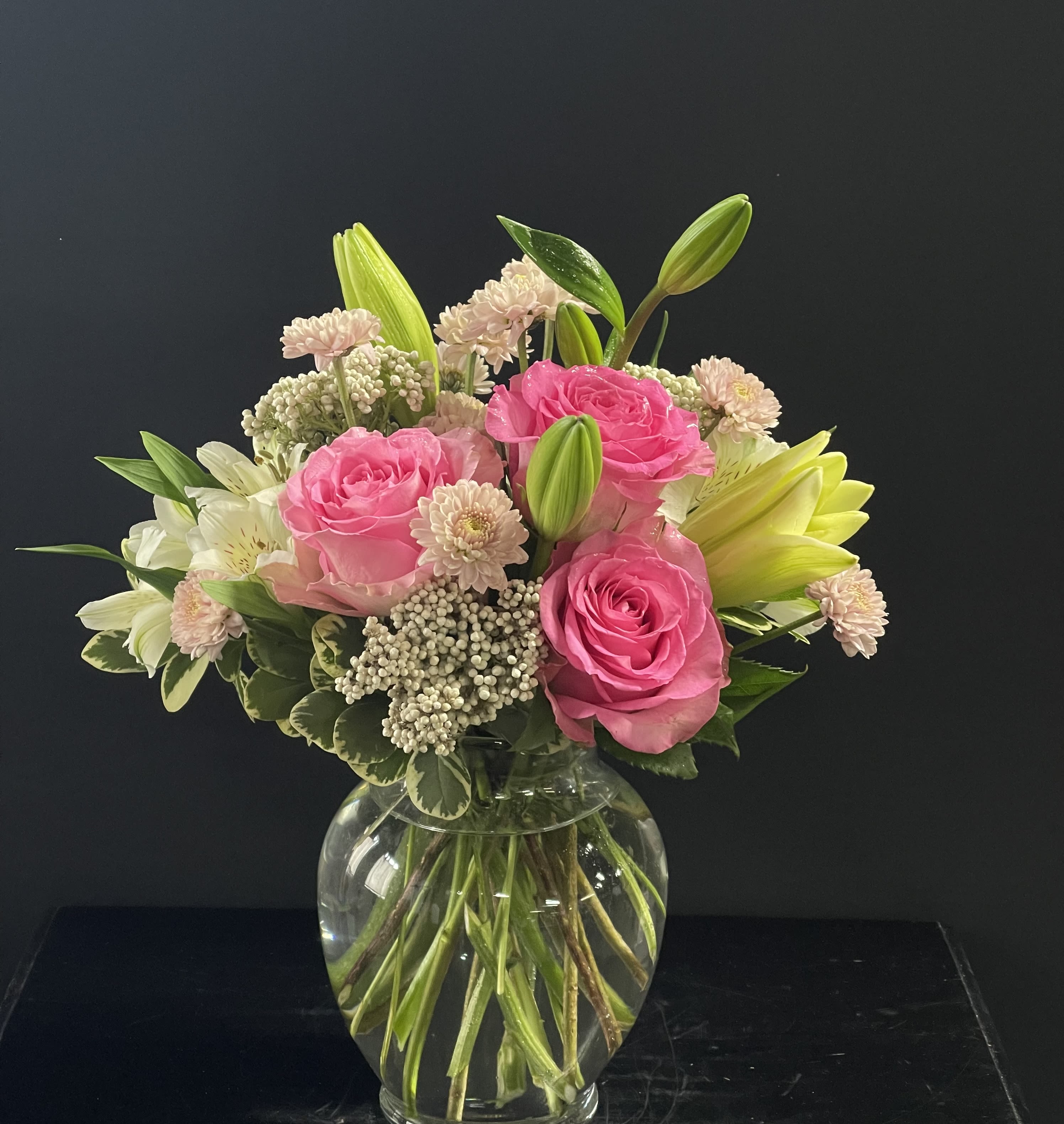 Arrive In Style - This beautiful bouquet will most certainly arrive in style! Ready for the runway, as it were. A delightful combination of light colors and lovely flowers, it's simply beautiful. Light pink roses, white asiatic lilies, alstroemeria, cushion spray chrysanthemums and statice are delivered in a stylish vase. Style to spare! Approximately 10 1/2" W x 11" H 