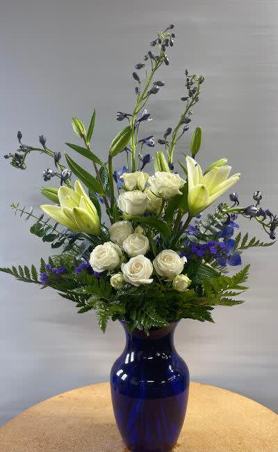 Cool Blue - This blue vase is filled with white and blue blooms!  White lilies, blue delphinium, white spray roses and purple statice with lush greens.