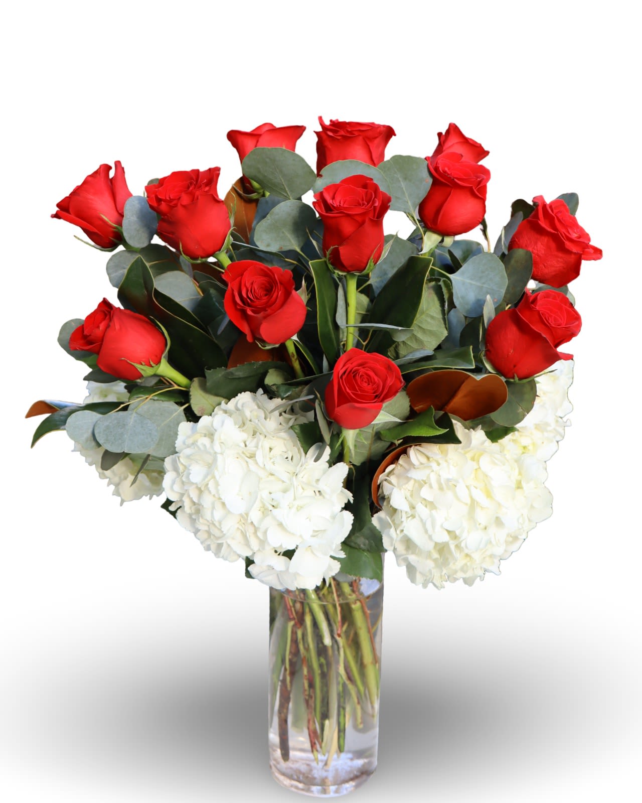 Timeless Romance   - This elegant arrangement combines premium red roses with cloud-like white hydrangea and textured greenery. Designed in a clear glass vase, it offers a clean, luxurious look that feels both classic and modern. Crafted with care and intention, this is not an ordinary rose bouquet it is a statement of quality and design. 24”H.  22”W