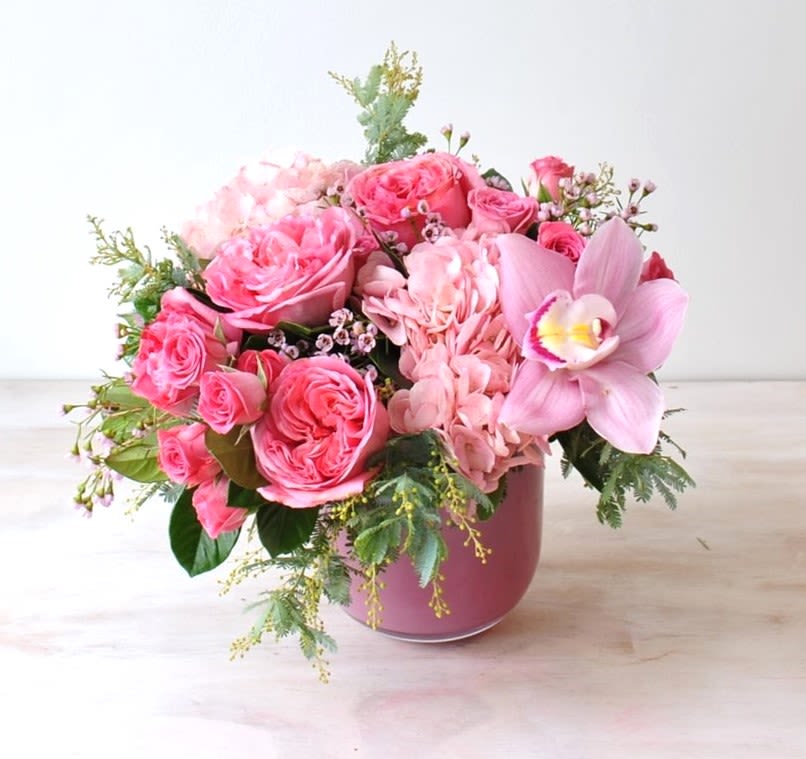 Cupid's Bloom - A sweet arrangement of pink cymbidium orchids, garden roses, and hydrangeas, in a glass vase. Perfect for Valentine's Day!