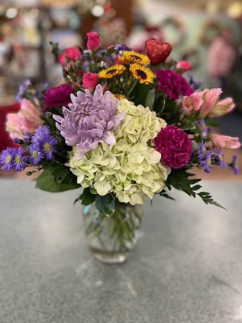 Spring (SP) - Our clear glass 8 in vase is filled with garden favorites such as Hydrangea, Roses, alstroemeria, carnations and more.