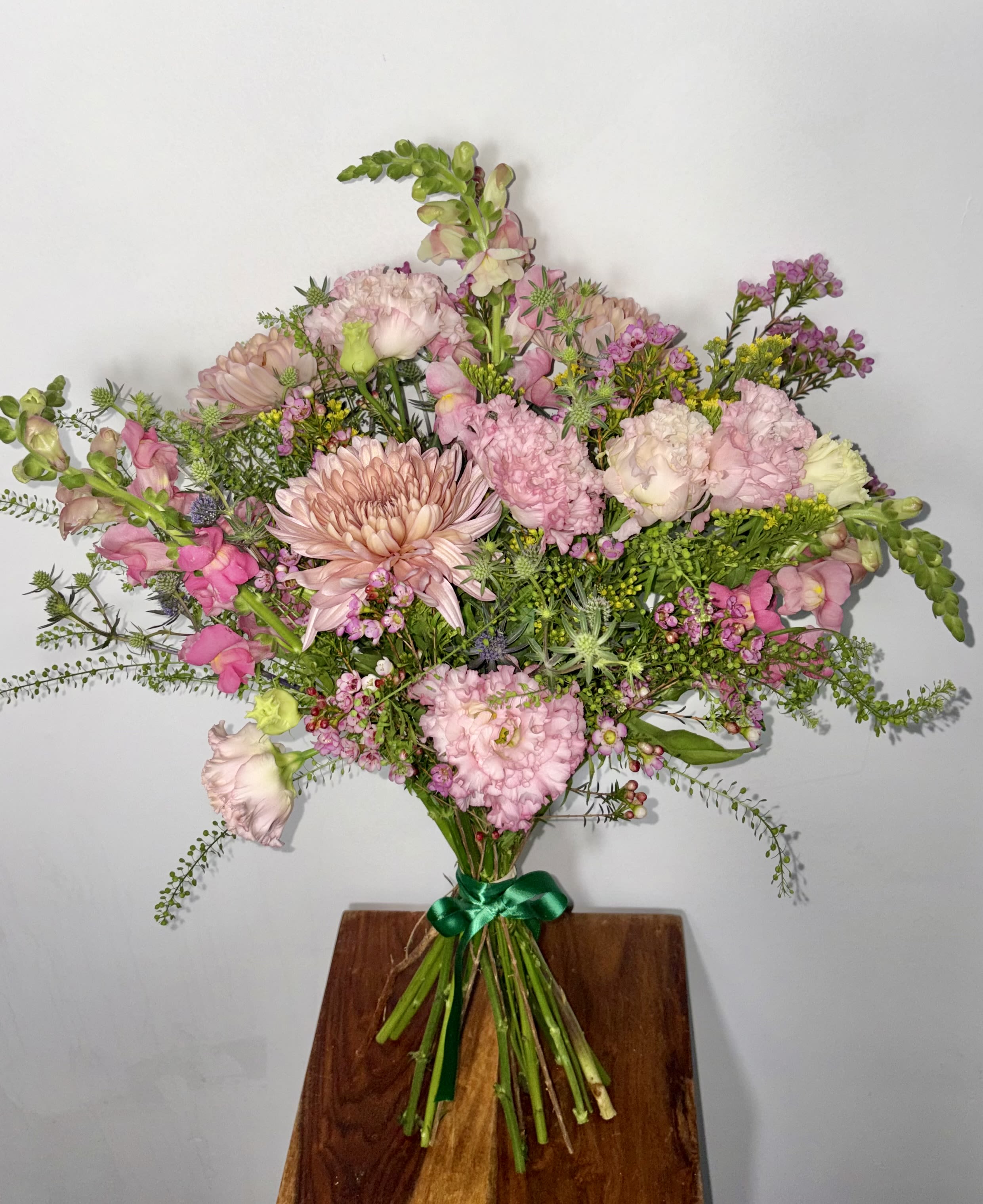 Pretty in Pink  - Soft, joyful, and effortlessly charming, this Mixed Pink Floral Bouquet is a celebration of friendship and modern romance. A lush blend of frilly Lisianthus, Snapdragon, pink Wax Flower, Thistle, fragrant Gunni Eucalyptus, airy Penny Cress, and Heritage Mums creates a bouquet that feels both playful and refined. Perfect for a dear friend or your one-of-a-kind Valentine, it’s beautiful on its own—or go premium with the addition of pink Tulips or romantic Ranunculus for an extra layer of luxury and love.