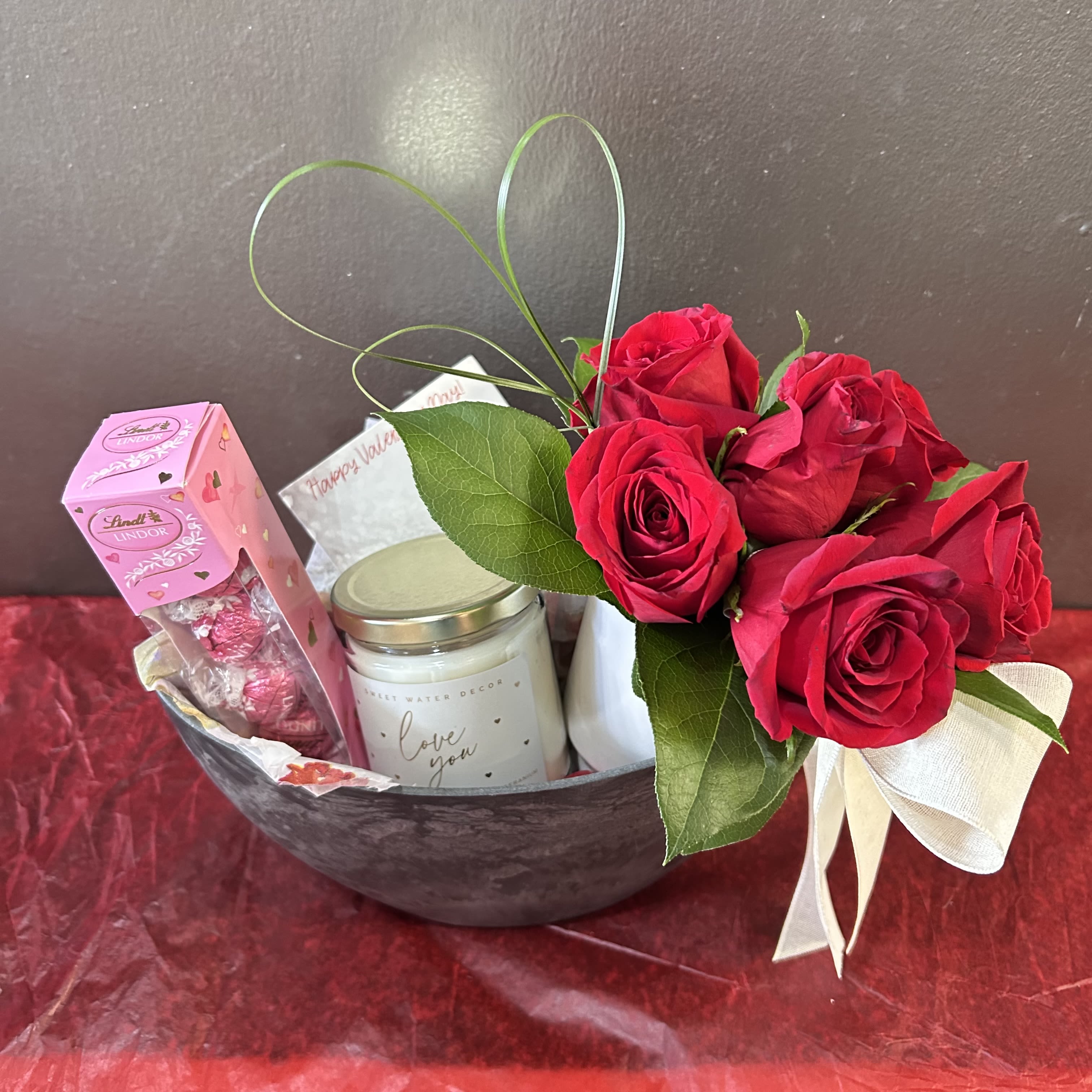 Romantic Valentine’s Day Gift Baskets - Enjoy one of our elegantly curated gift baskets featuring a bouquet of roses, accompanied by a luxurious scented soy candle and decadent chocolates.   Containers may vary, but will match theme of EITHER deep pinks/red roses or pastels with white roses.  Deluxe will also include a bag of loose rose petals and additional chocolates.