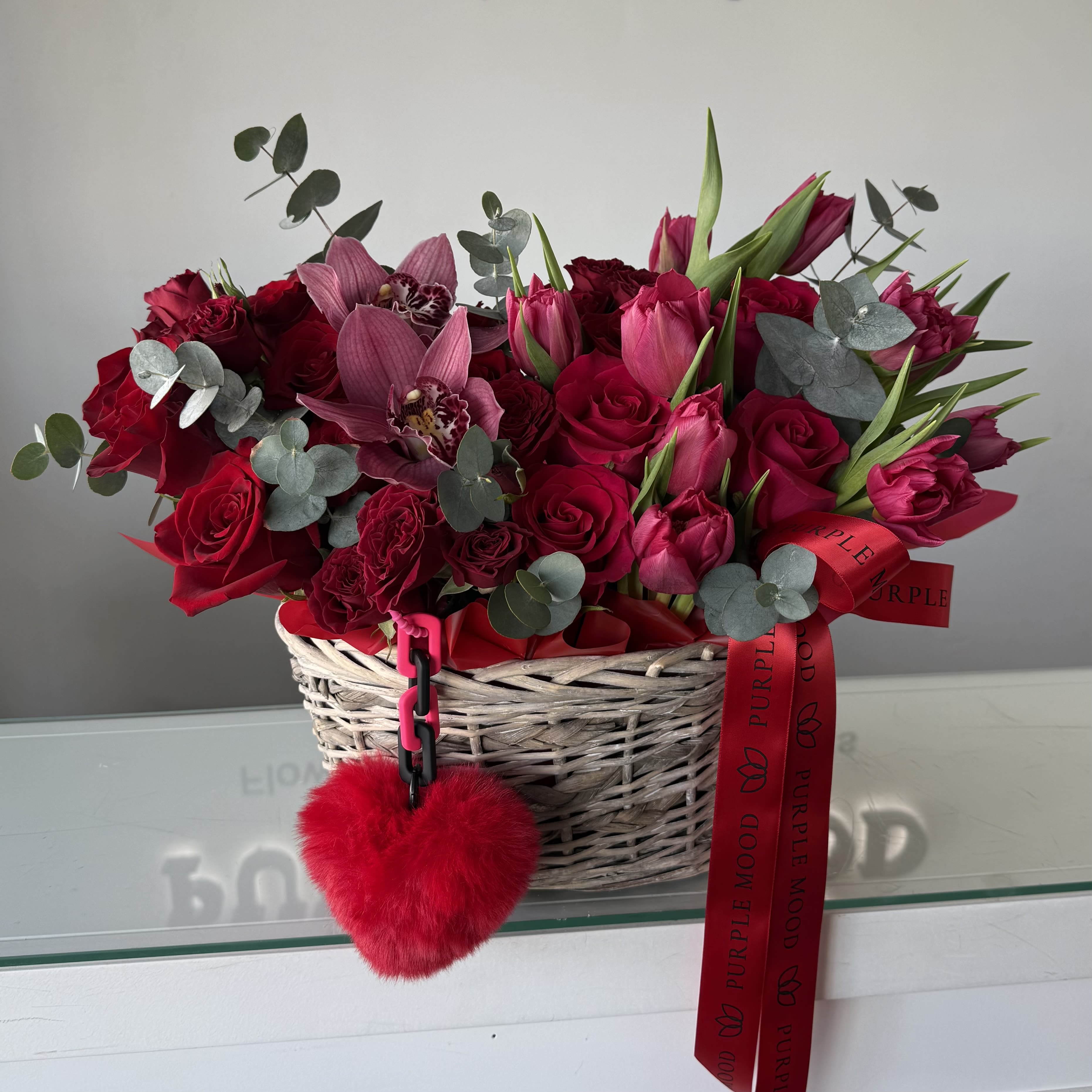 LOVE Basket -  A bold Valentine’s statement designed to impress. This luxurious basket features a curated selection of premium red and pink blooms, elevated with romantic accents and finished in Purple Mood’s signature style. Rich, expressive, and undeniably elegant — LOVE Basket is made for grand gestures and unforgettable moments.  Perfect for Valentine’s Day, anniversaries, or when words simply aren’t enough.  Flower selection may vary slightly based on seasonal availability while maintaining the same color palette and overall aesthetic. 