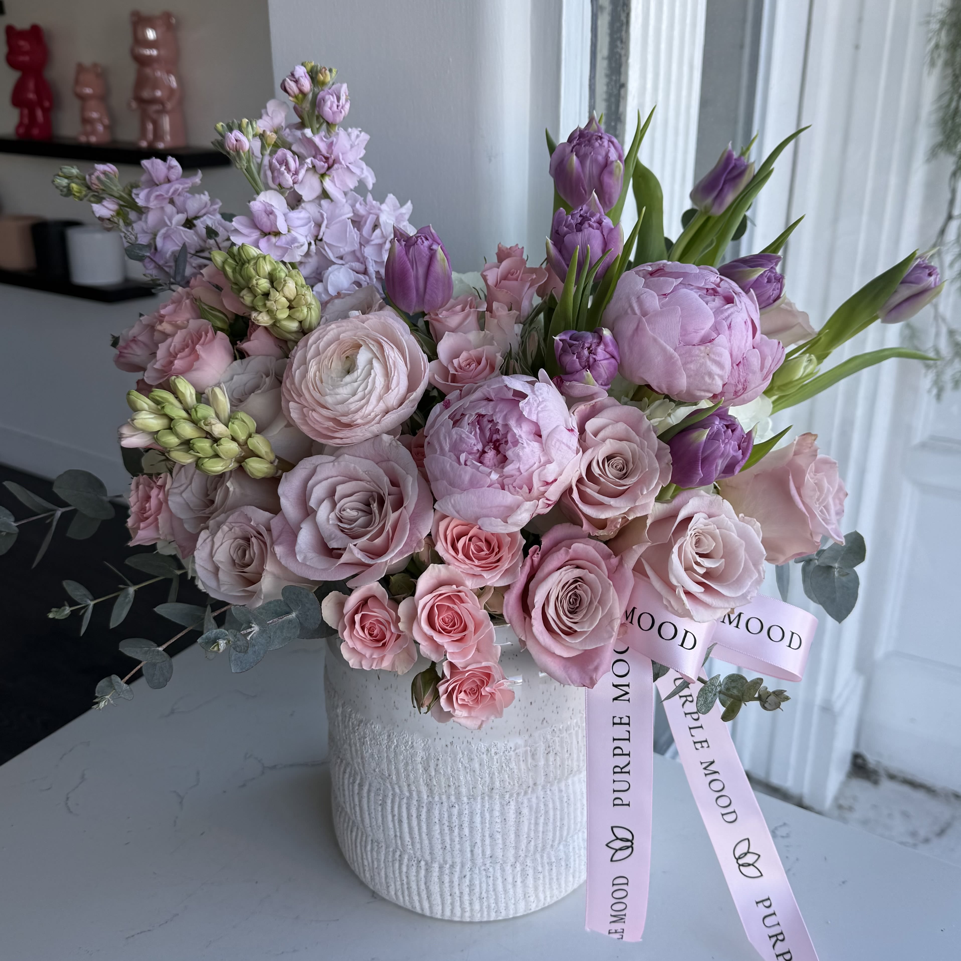 Blush Atelier Vase - A refined floral composition inspired by soft color palettes and couture aesthetics. This elegant arrangement features a delicate blend of blush and lavender blooms, layered textures, and airy seasonal florals, thoughtfully designed in Purple Mood’s signature style. Graceful, sophisticated, and effortlessly modern — Blush Atelier Vase is created for those who appreciate subtle beauty and elevated design.  Perfect for Valentine’s Day, anniversaries, birthdays, or meaningful everyday moments.  Flower selection may vary slightly based on seasonal availability while maintaining the same color palette and overall aesthetic. 