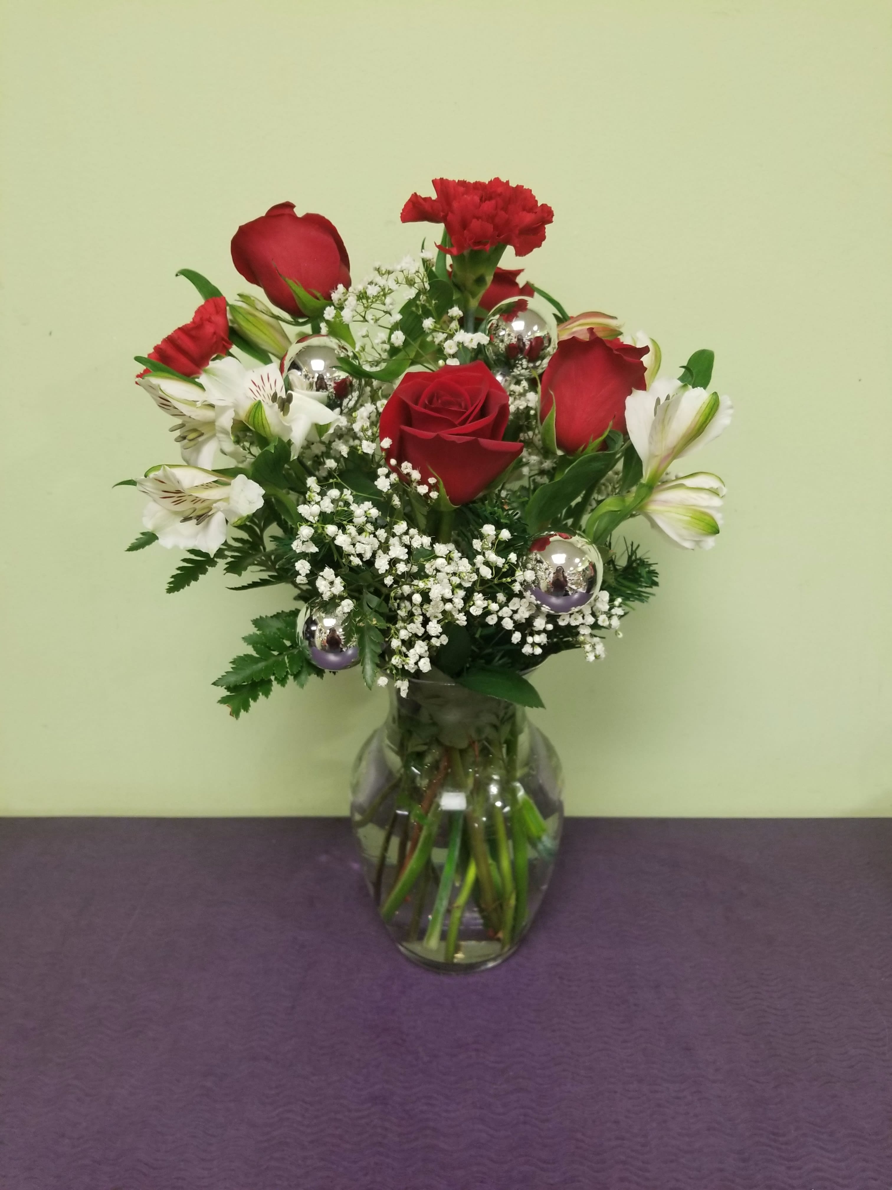 Christmas Cheer - This cheery arrangement will get you in the mood for the holiday. Includes roses, Christmas ornaments and more. 