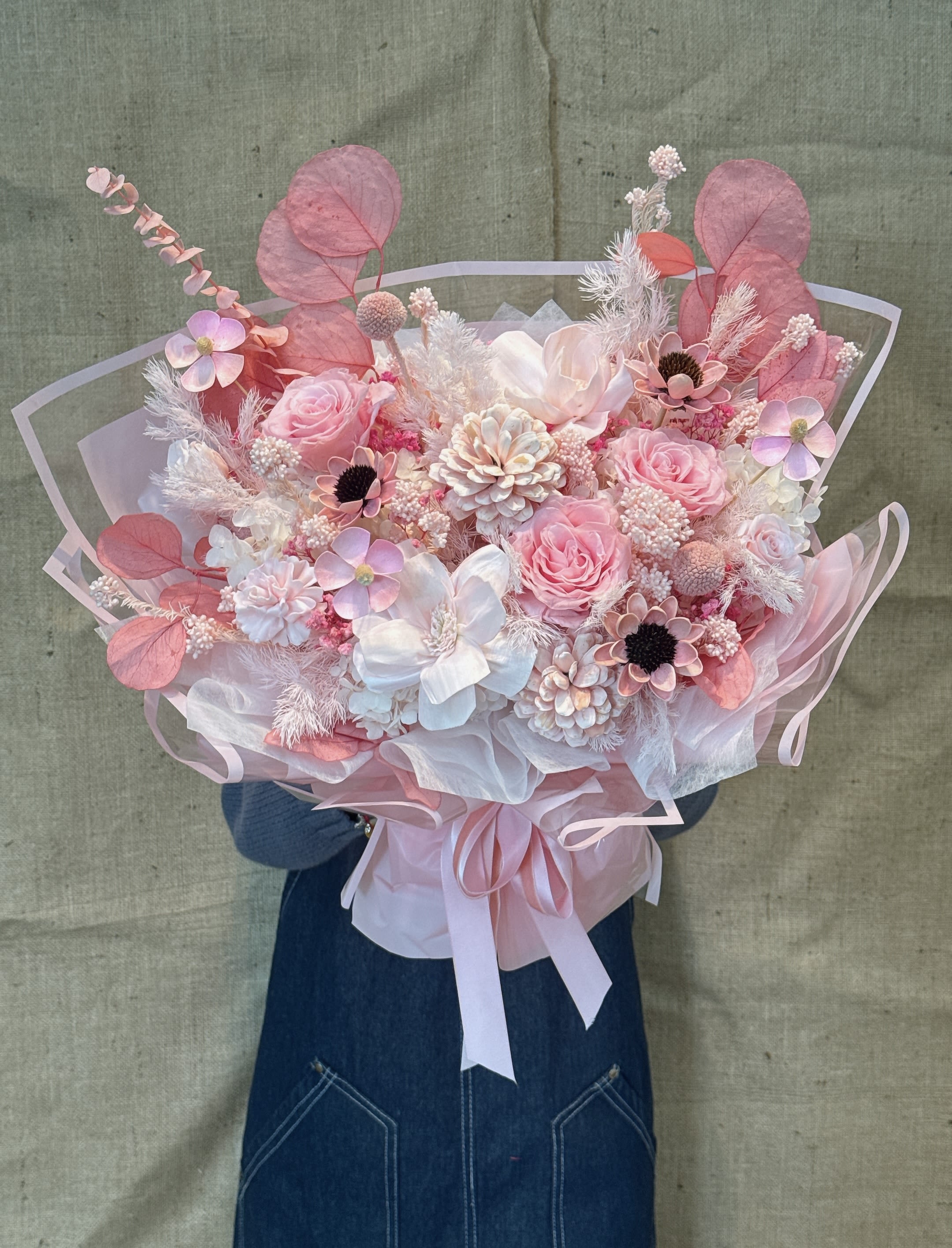 Sweet Remains - This is an immortal flower/dried flower bouquet with a soft pink tone. It mixes different forms of flowers, mainly including pink roses (eternal roses) and white, beige or light yellow fluffy flowers (such as full stars, hydrangeas or feather grass). Main characteristics: Color: The overall appearance is soft and romantic pink and white, and the color matching is warm and elegant. Flower material type: a combination of immortal flowers (real flowers are treated by special technology and can be preserved for 3-5 years) and natural dried flower materials. Packaging: The bouquet is made of transparent and light pink wrapping paper, with light ribbon bows, Korean style and exquisite. Meaning: Pink immortal flowers usually symbolize eternal love, romance and delicate feelings. Due to its durability, it also implies love that never withers or eternal emotion.