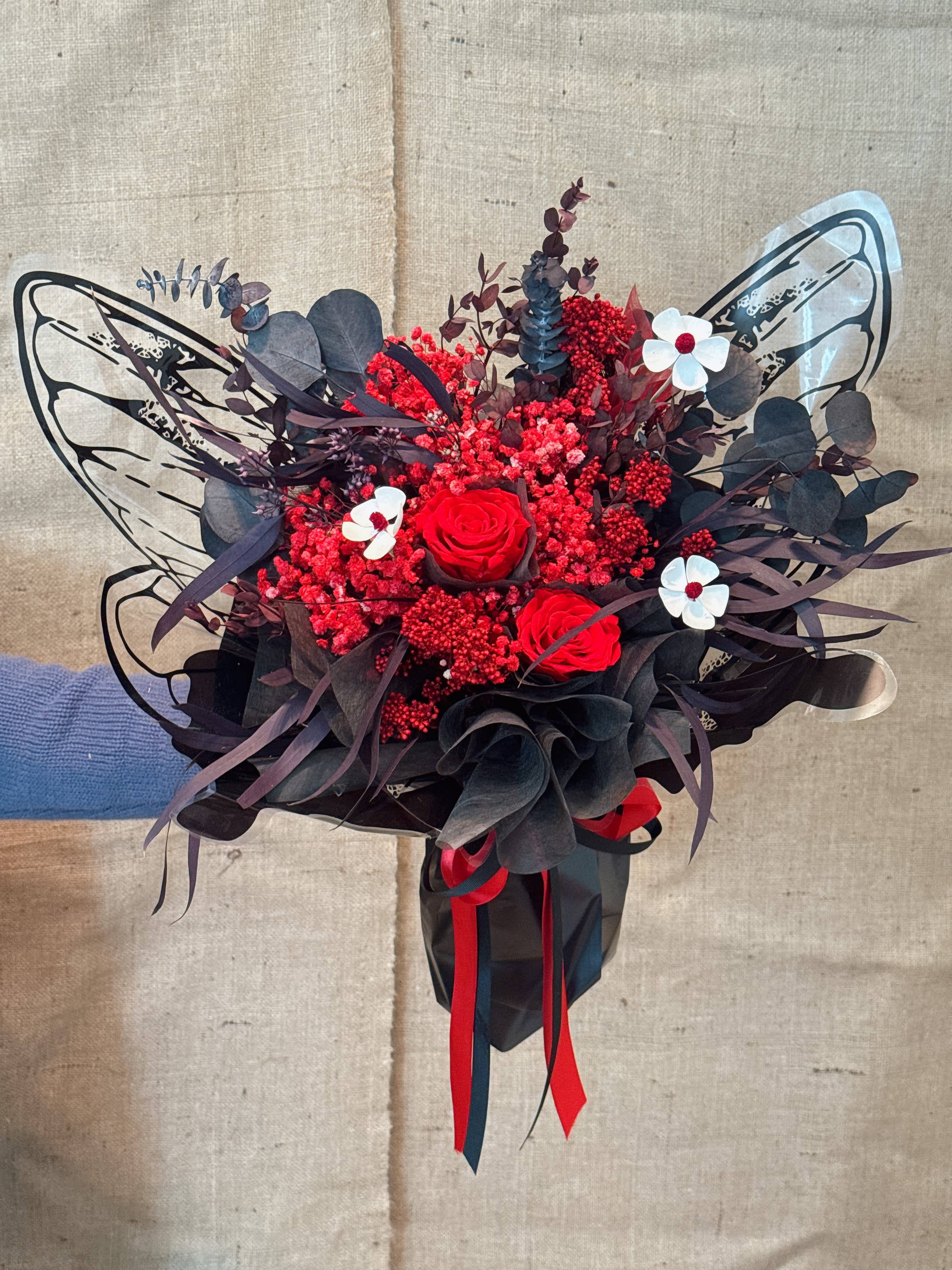 Red In Black - This is a mixture of red flowers with a variety of different textures and shapes, including the main flowers similar to roses, as well as all kinds of fluffy, feather-like flowers and leaves. Main characteristics: Color: The whole presents a rich and warm red tone. Flower material type: including immortal flowers (after special technical treatment to retain the appearance and touch of flowers) and natural dried flowers. Packaging: The bouquet is wrapped in red wrapping paper and tied tightly with ribbons, which is modern and passionate. Meaning: Red bouquets usually symbolize passionate love, passion, love, romance and courage. Because it is an eternal flower, it also implies love that never withers or eternal emotion. 