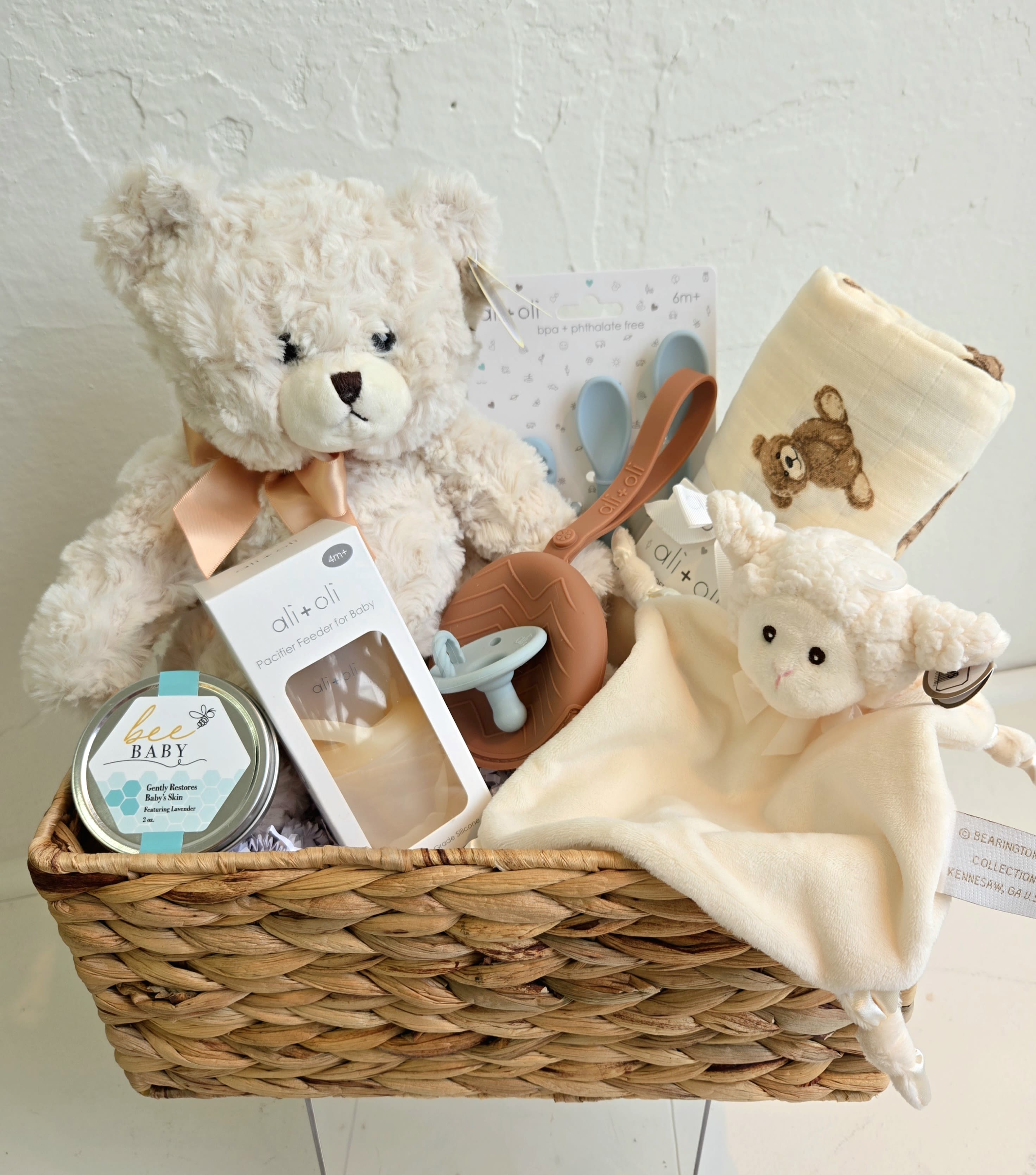 Baby Gift Basket in Boy or a Girl Colors - This curated basket is crafted with baby boy colors or the exact same items but in pinks.  Its has the softest medium sized bear with a soft gold bow, a swaddle blanket with bears (or a pink for a girl), Bee Baby lavender skin balm from Sister Bees, pacifier feeder, pacifier, pacifier holder and a little lovie lamb for soothing and comfort.  A new parent would LOVE this gift.
