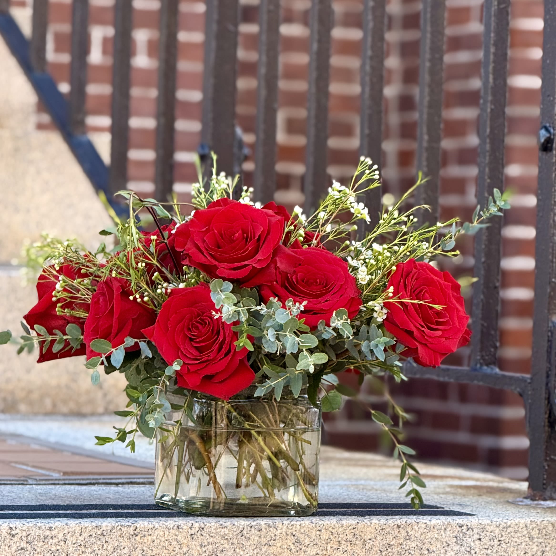 Timeless Red Roses - One dozen premium red roses are artfully arranged with fresh greenery in a low ceramic vase. A timeless expression of love and elegance, perfect for any romantic occasion. Featuring: - Ecuadorian Roses - Styled with premium seasonal foliage Presentation Options: Clear square vase measuring approximately 5"H. (vase included in price). Every order includes: A custom message card - simply enter your message at checkout and we'll take care of the rest.  As a local florist in Charleston South Carolina, everything is made fresh by us here at our flower shop Downtown Charleston.