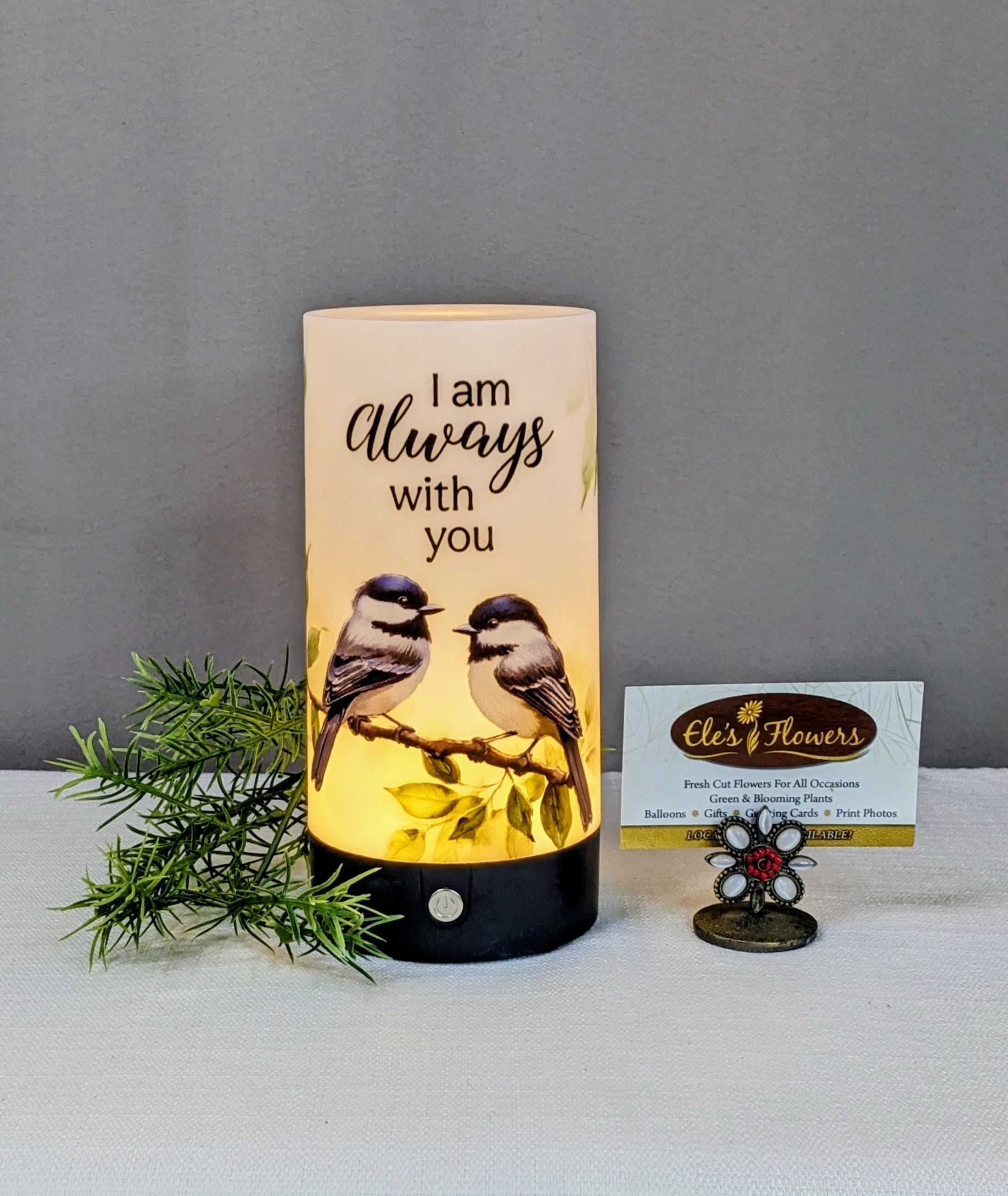 Always with You - Tabletop Lantern  - This lightweight tabletop cylinder lantern is a comforting keepsake designed to bring peace and reassurance through gentle light. Featuring three touch-activated lighting settings, it allows you to easily adjust the glow to create a warm and soothing atmosphere.  Printed with the heartfelt words, “I am always with you,” the lantern is adorned with a tender illustration of a pair of chickadees perched together on a leafy branch. Symbolizing companionship, love, and presence, this design offers a meaningful reminder that those we cherish are never truly far away. Perfect for a bedside table, mantel, or as a sympathy gift, this lantern provides a quiet sense of comfort and enduring connection.  Approximate Dimensions: 7 1/4"H x 3 1/2"D