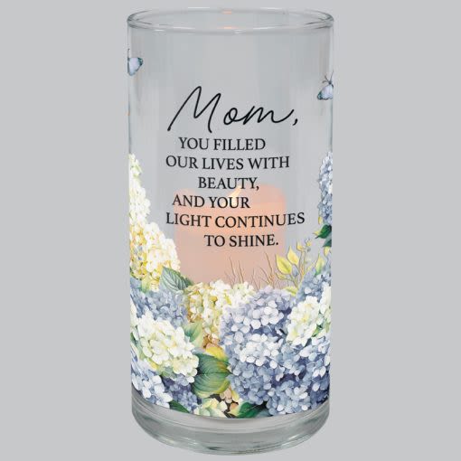 Mom Hurricane Candle - These hurricane candles are made of glass with UV printed artwork. The included candle has a flameless LED flickering flame that runs on an automatic timer 6hrs ON and 18hrs OFF. The required CR2032 battery IS included. H: 7.25" DIA: 3.5".  Reads "Mom, you filled our lives with beauty, and your light continues to shine."