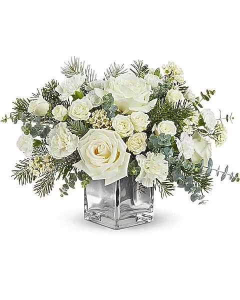 Teleflora's Arctic Blooms Bouquet - Arctic Blooms Bouquet glows with white roses, winter greens, and frosty details in a stylish silver cube. A peaceful and elegant gift or Christmas decoration for cozy seasonal gatherings. Arctic Blooms Bouquet features white roses, white spray roses, white carnations, white miniature carnations, white waxflower, spiral eucalyptus, and noble fir-arranged in a silver cube vase for winter elegance.   Orientation : All-Around  All prices in USD ($)  Due to an increase in the cost of roses, some product prices may be impacted during the Valentine’s delivery period.