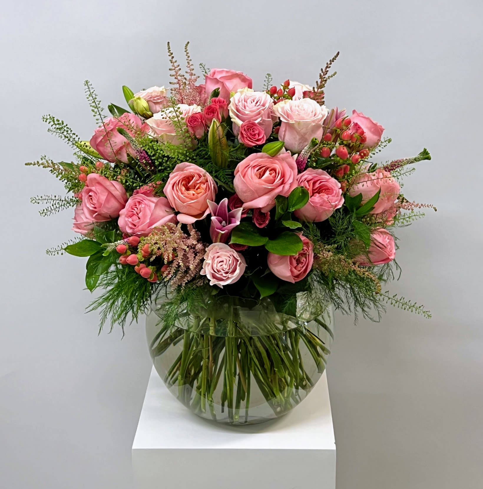 Pink Sensation - Imagine a stunning flower arrangement that combines the delicate beauty of pink roses, pink lilies, and spray roses in a charming fishbowl vase. This arrangement exudes elegance and grace, perfect for bringing a touch of romance and sophistication to any space. The soft pink hues of the roses and lilies complement each other beautifully, creating a harmonious blend of colors. The addition of spray roses adds texture and depth to the arrangement, making it a true masterpiece. Placed in a clear fishbowl vase, this arrangement not only showcases the beauty of the flowers but also adds a modern and unique touch to the overall presentation. This arrangement is a perfect choice for anyone who appreciates the timeless beauty of fresh flowers and the art of floral design