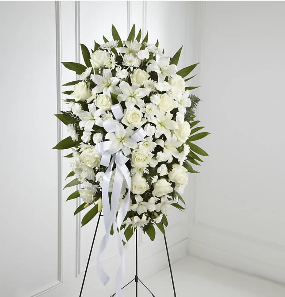 Exquisite Tribute  - The Exquisite Tribute Standing Spray is an elegant display of sweet serenity. White roses, Asiatic lilies, chrysanthemums and mini carnations are artfully arranged amongst emerald palm fronds and lush greens. Accented by white satin ribbon and standing on a wire easel, this standing spray is an outstanding way to honor the life of your loved one.   SUBSTITUTION POLICY Always deliver the freshest flowers! Please note the bouquet pictured reflects our original design.  If the exact flowers or container in this arrangement are not available, our local florists will create a beautiful bouquet with the freshest available flowers.