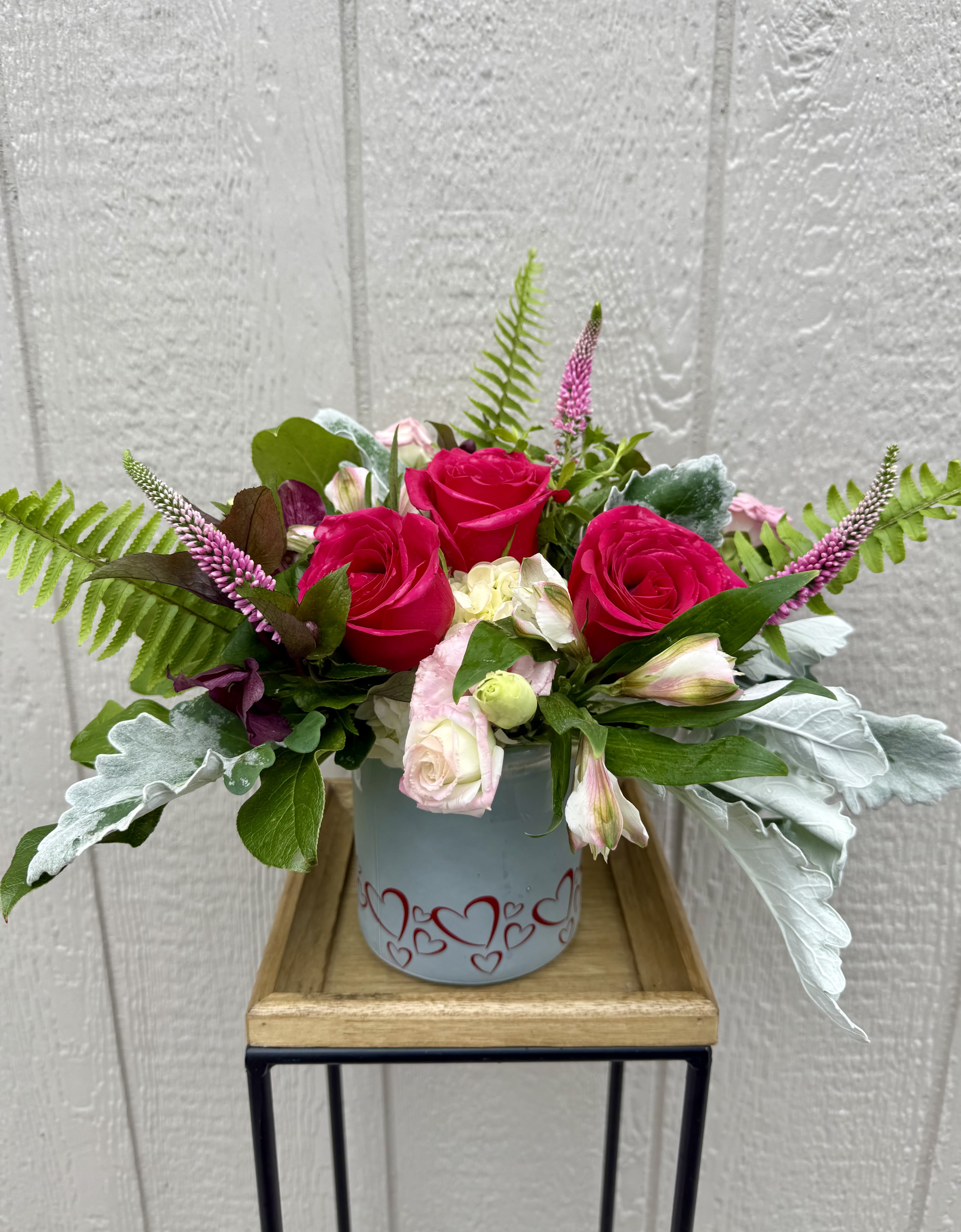 Hot Momma - Heart cylinder container consisting of hot pink roses, other soft pink florals and greens put together to make a sweet Mother’s Day arrangement.  *Premium will contain peonies. 
