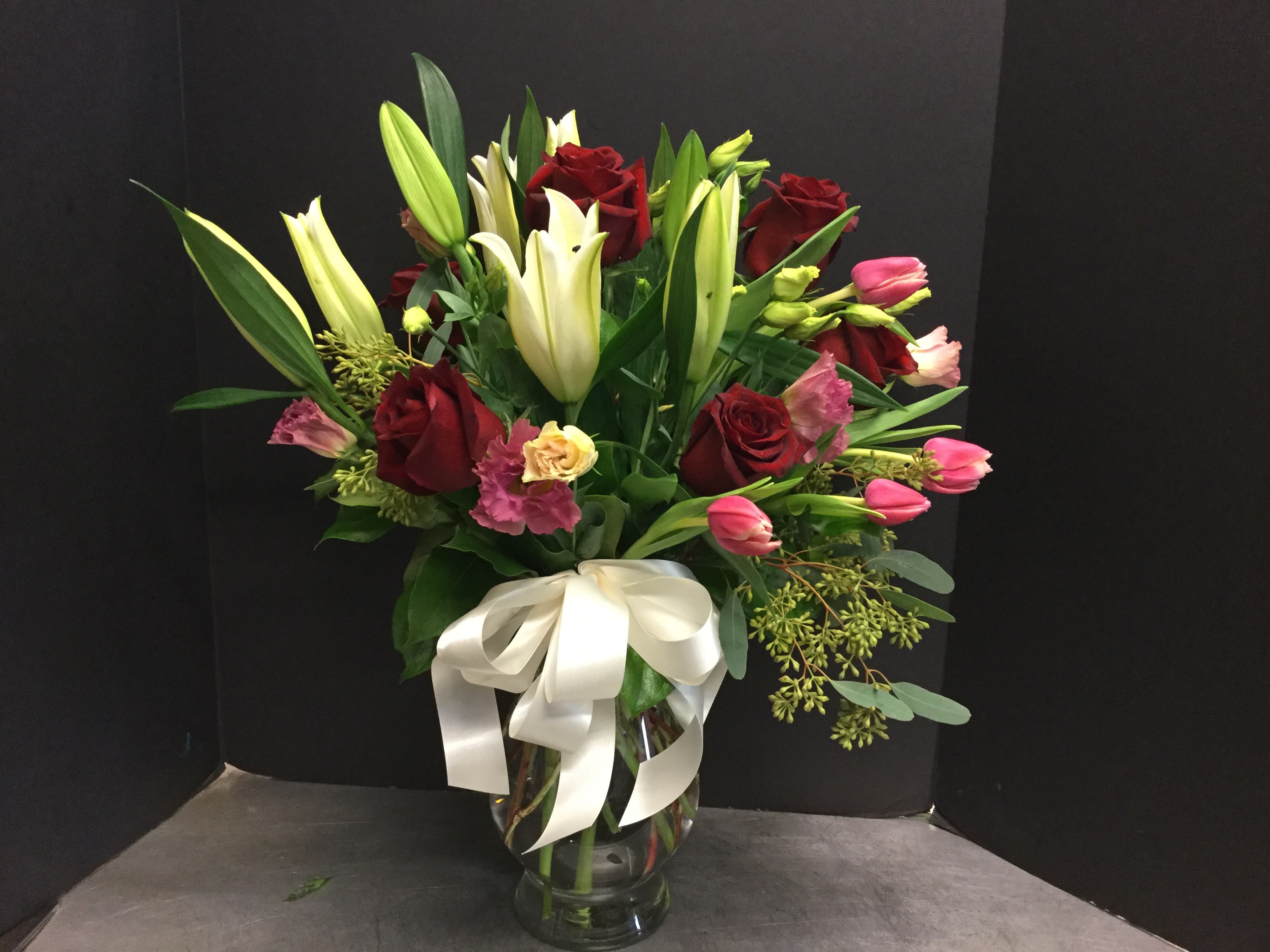 Hot Nights - White lilies, red roses, lisianthus, pink tulips in a tall vase.