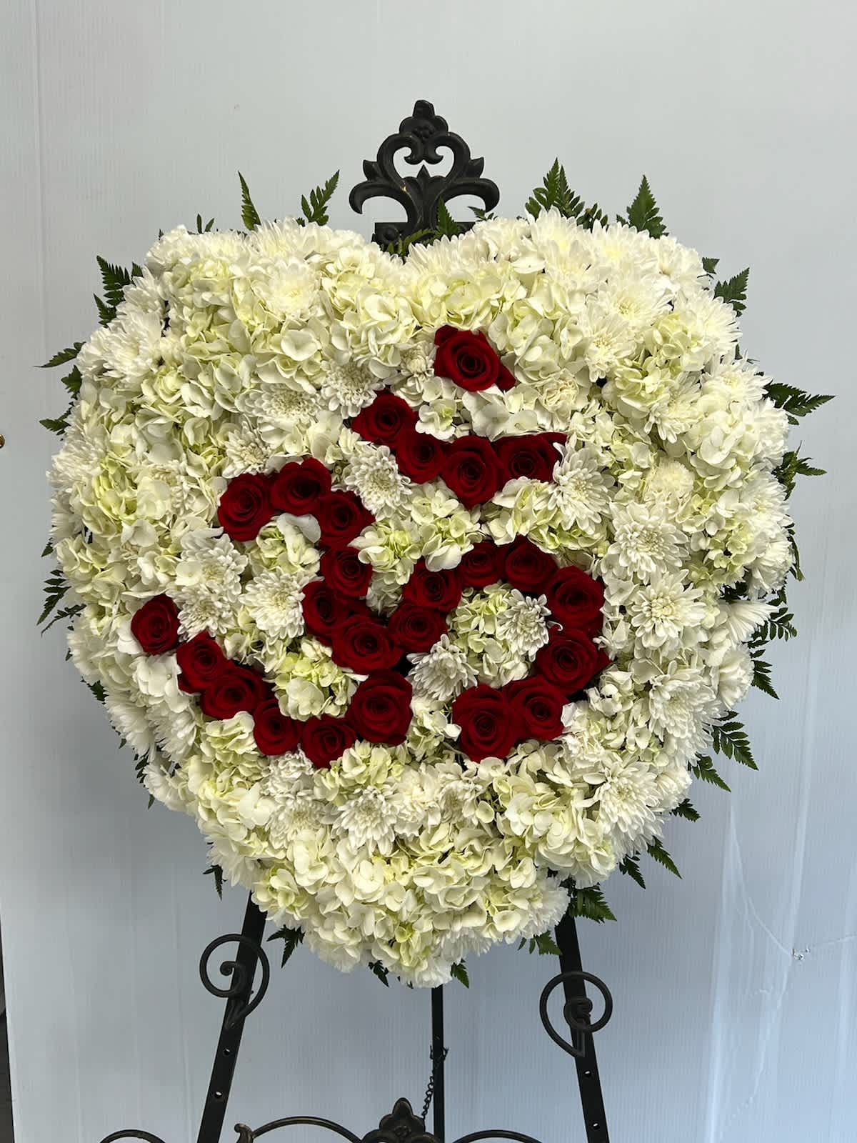 AUM Standing Spray - Heart shaped back drop with the AUM done in roses.  Please note: Flower varieties and colors may be substituted based on seasonal and daily availability. We always ensure your arrangement is of equal or greater value and just as beautiful.