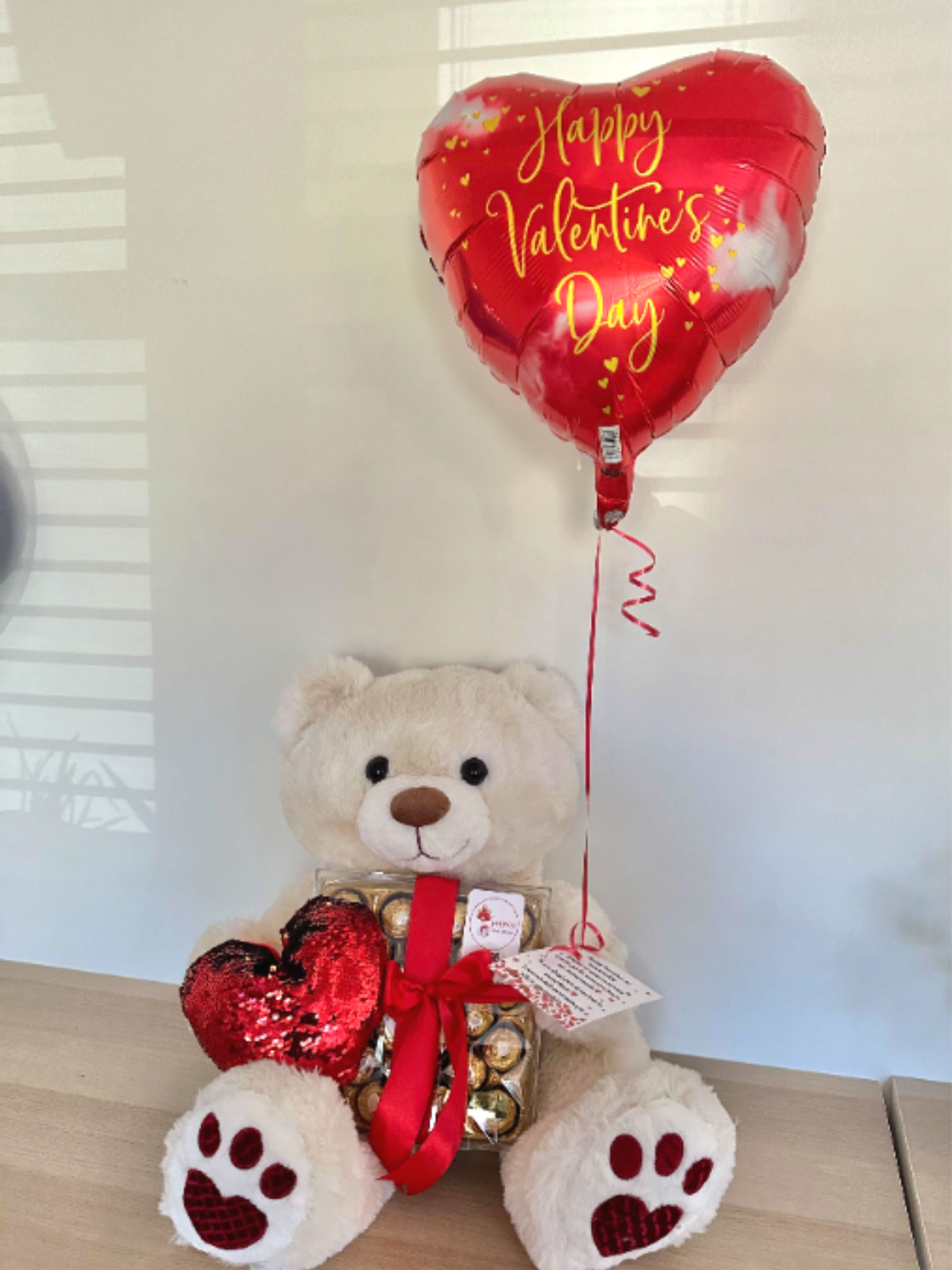 Happy V Day - Surprise your someone special with a gift that has it all. The 'Happy V Day' arrangement combines chocolates with a 20" soft plush companion and a festive Valentine’s balloon, creating a memorable moment.  Sorprende a esa persona especial con un regalo que lo tiene todo. El arreglo "Feliz Día de San Valentín" combina chocolates con un peluche de 50 cm y un globo festivo de San Valentín, creando un momento memorable