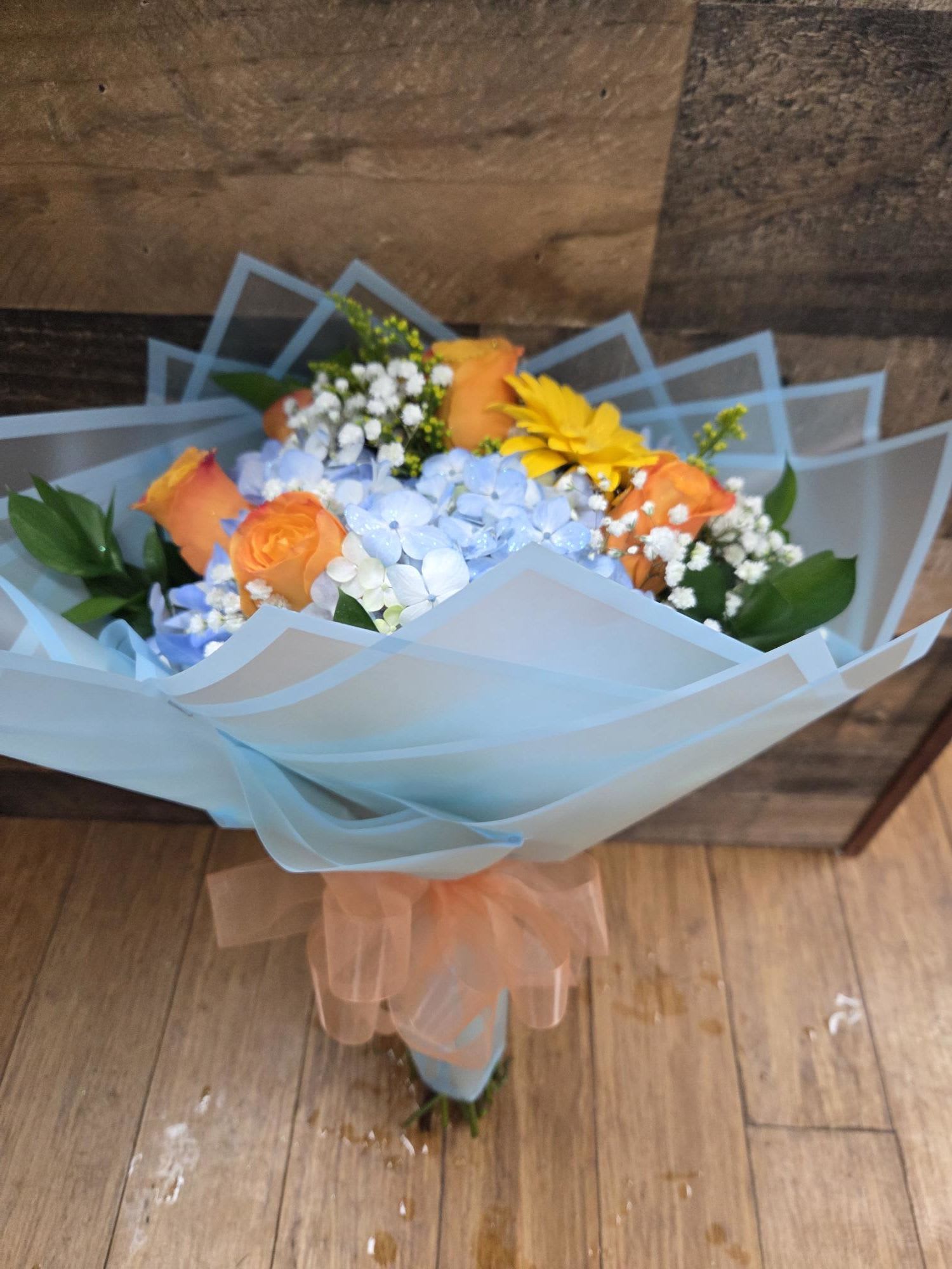 orange hand bouquet - blue hydrangeas, orange roses, yellow gerberas fillers and greens