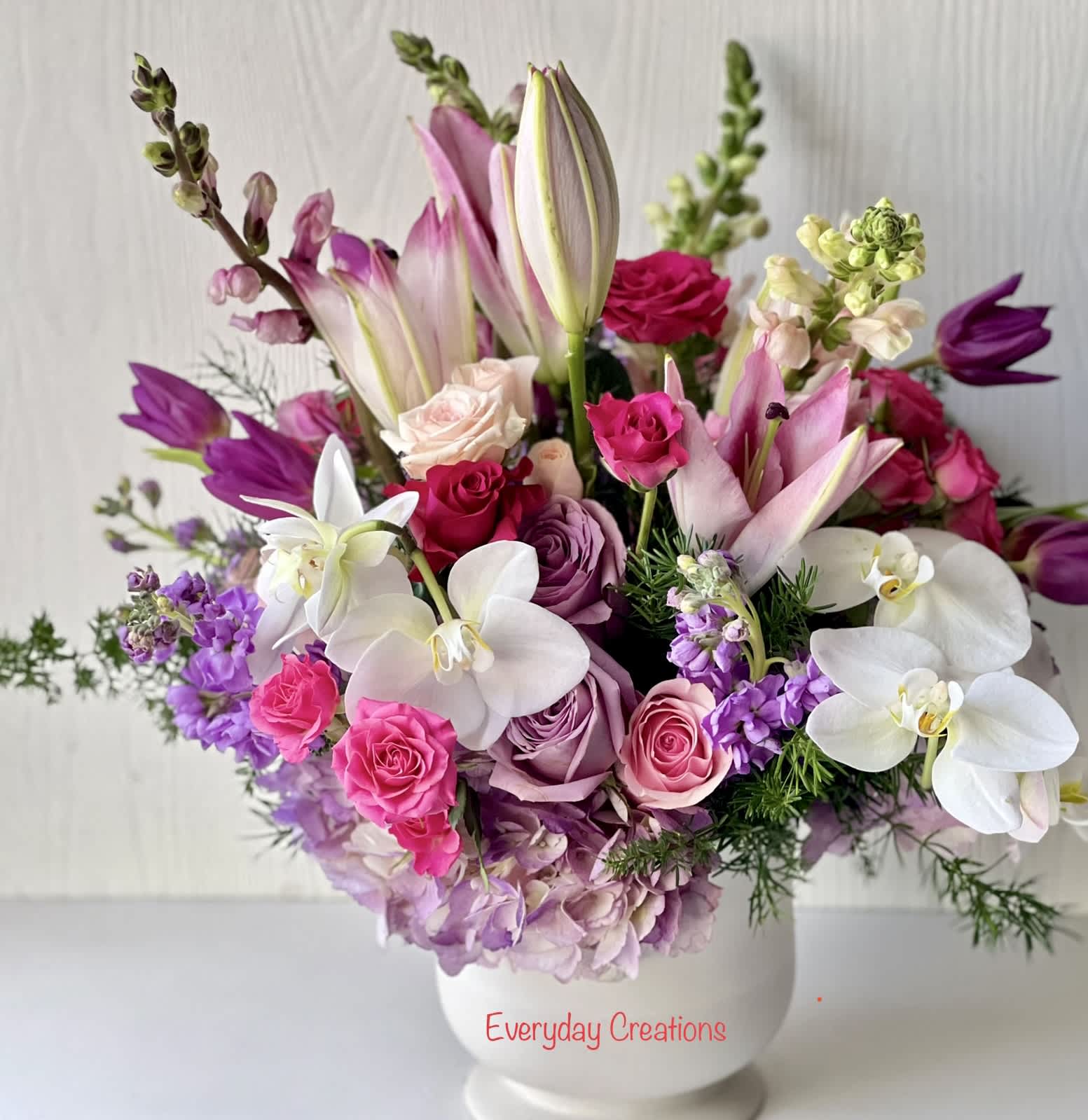 EC14 - Ever After Bouquet - Live happily with the Ever After Bouquet. The bouquet features a stunning assortment of purple, blue and white flowers that complement each other perfectly. The gorgeous lilies, snapdragons, hydrangeas and roses in shades of purple, pink and white come together in perfect harmony and create a true work of art. The Ever After Bouquet is designed in a white ceramic vase. Approximate Dimemsions:11" w X 16" h   