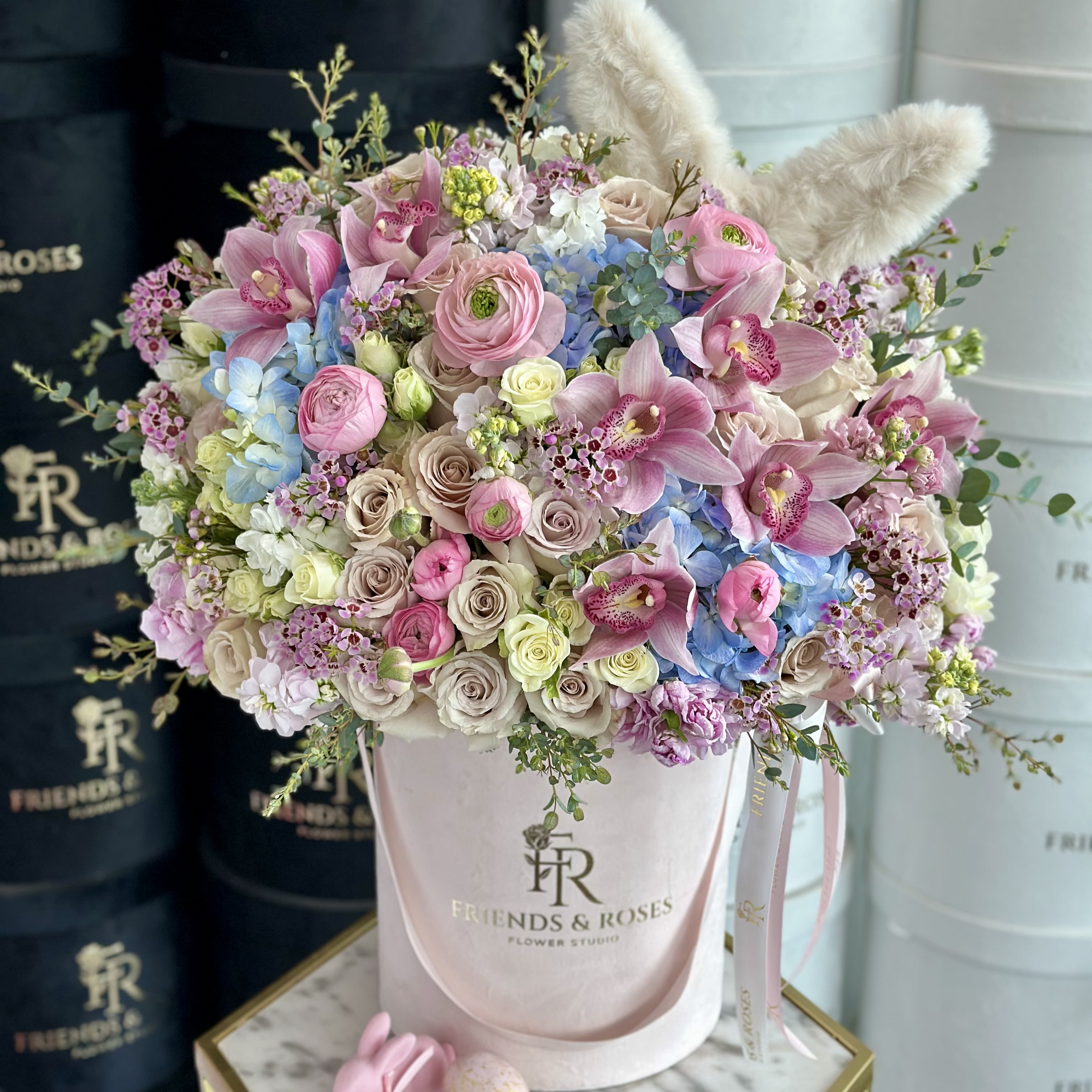 Bunny Twist - A beautiful Easter bouquet in a box, showcasing an elegant arrangement of premium flowers in soft pastel hues. The delicate blooms are thoughtfully arranged to create a harmonious and sooting display, perfect for celebrating the season. Each flower adds a touch of  freshness and grace, making the bouquet a charming and refined for the holiday.
