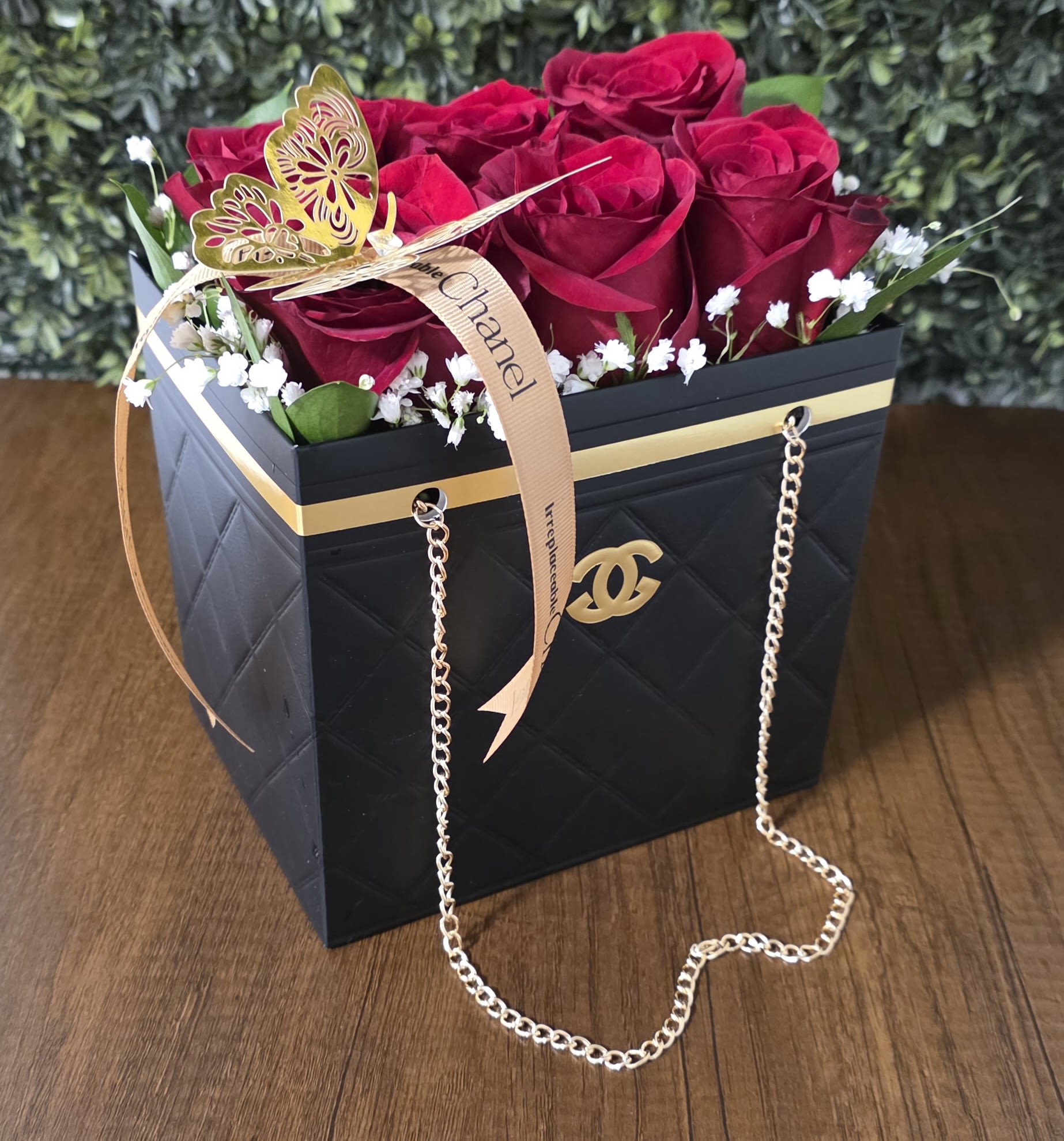 Black Chanel Bag - Vibrant roses, delicate baby's breath, lush greenery, and a gold butterfly accented with a Chanel ribbon.